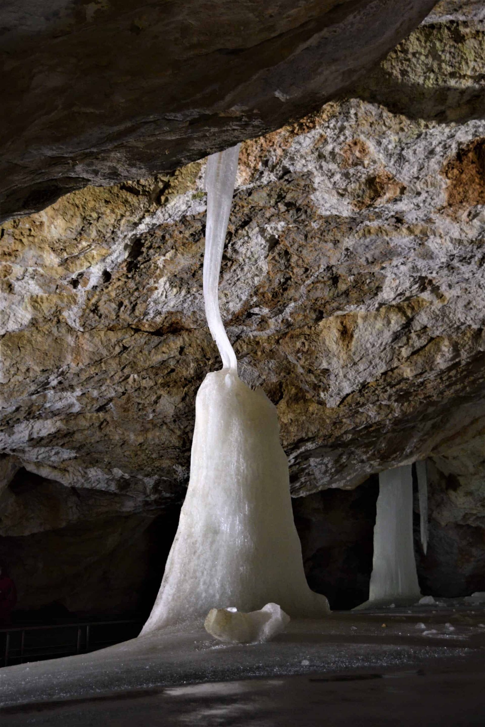 a ghostly looking ice mount connects to the ceiling via a thin frozen ice strand (back view), Dobsina Ice Cave, Slovakia