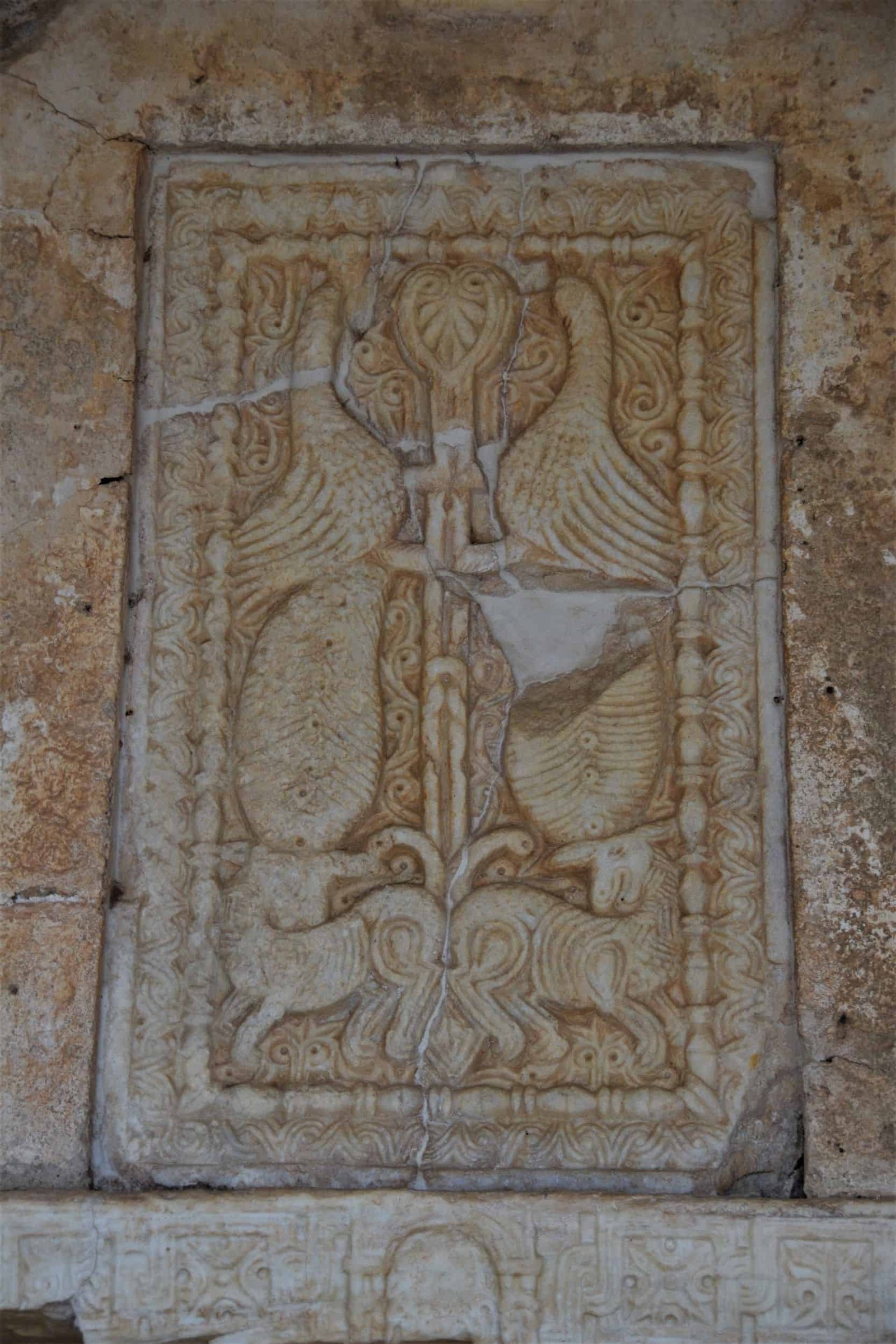 intricate adornment carved into a stoen wall showing two birds and cows, Greece