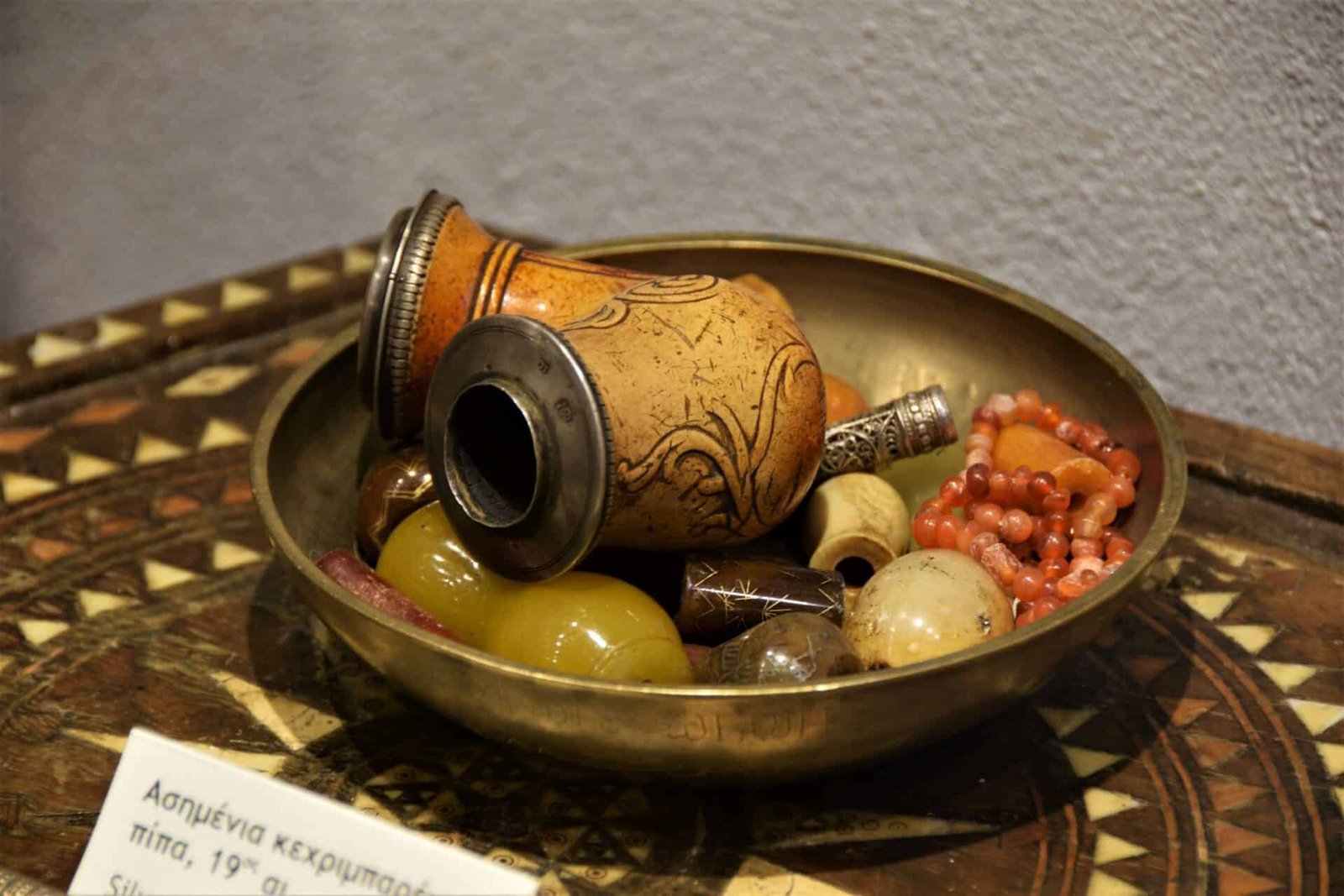 small adorned pipe in a bronze bowl surrounded by amber jewellery