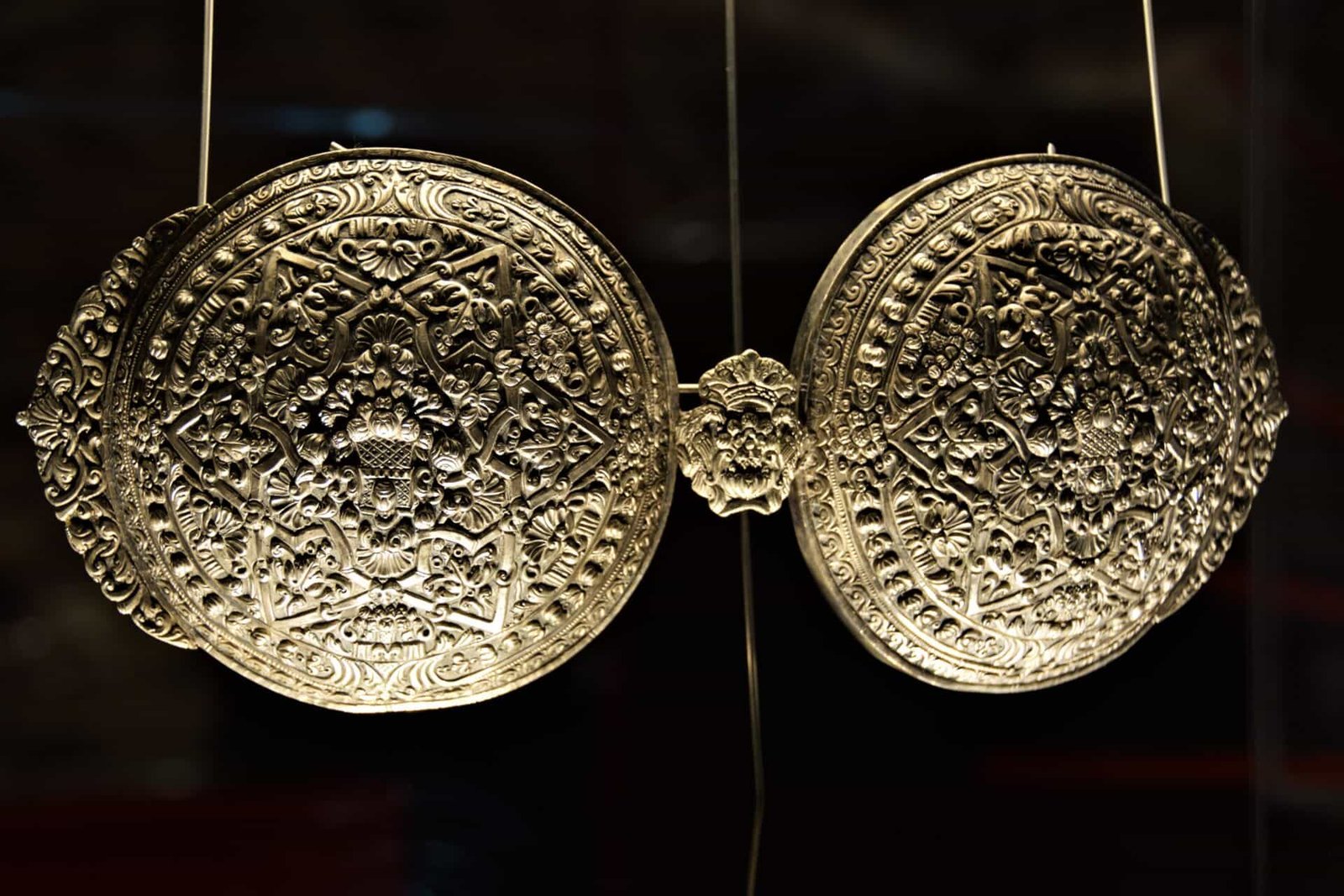 richly decorated silver belt buckle made of two large round pieces joind together in the middle by a smaller piece