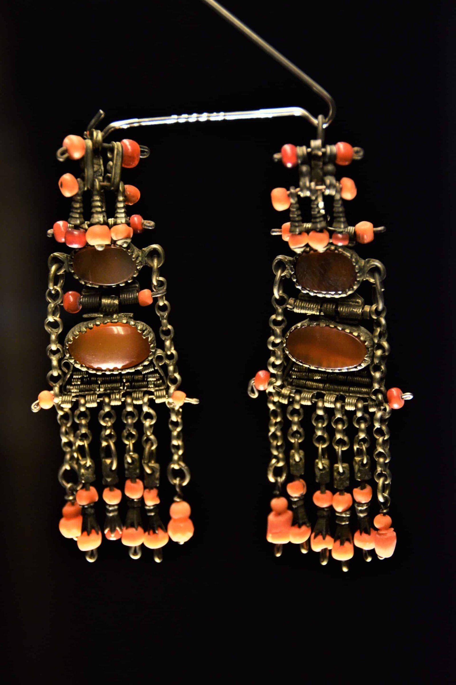 set of big blackened silver ear rings adorned with two big and several smaller orange and red gems