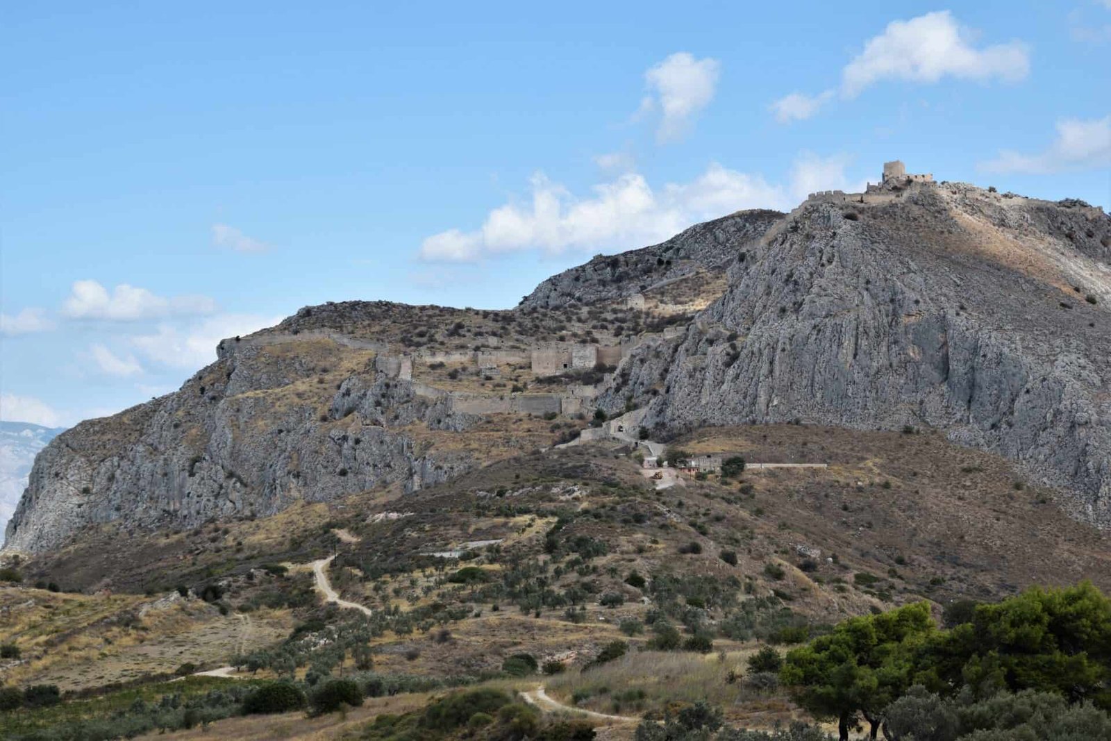 three massive walls, flanked by steep cliffsides, block of the sole entrance to the top of a table mountain boasting a stone watch tower on one peak