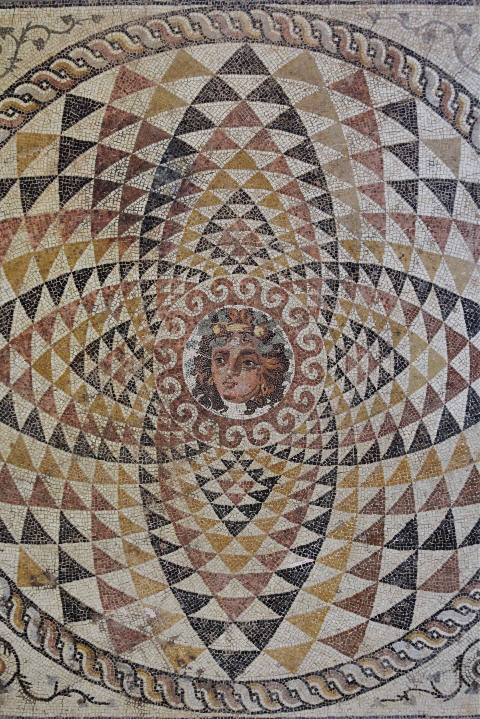 red, yellow, black, and white mosaic showing geometrical patterns circling around the head of a redheaded boy