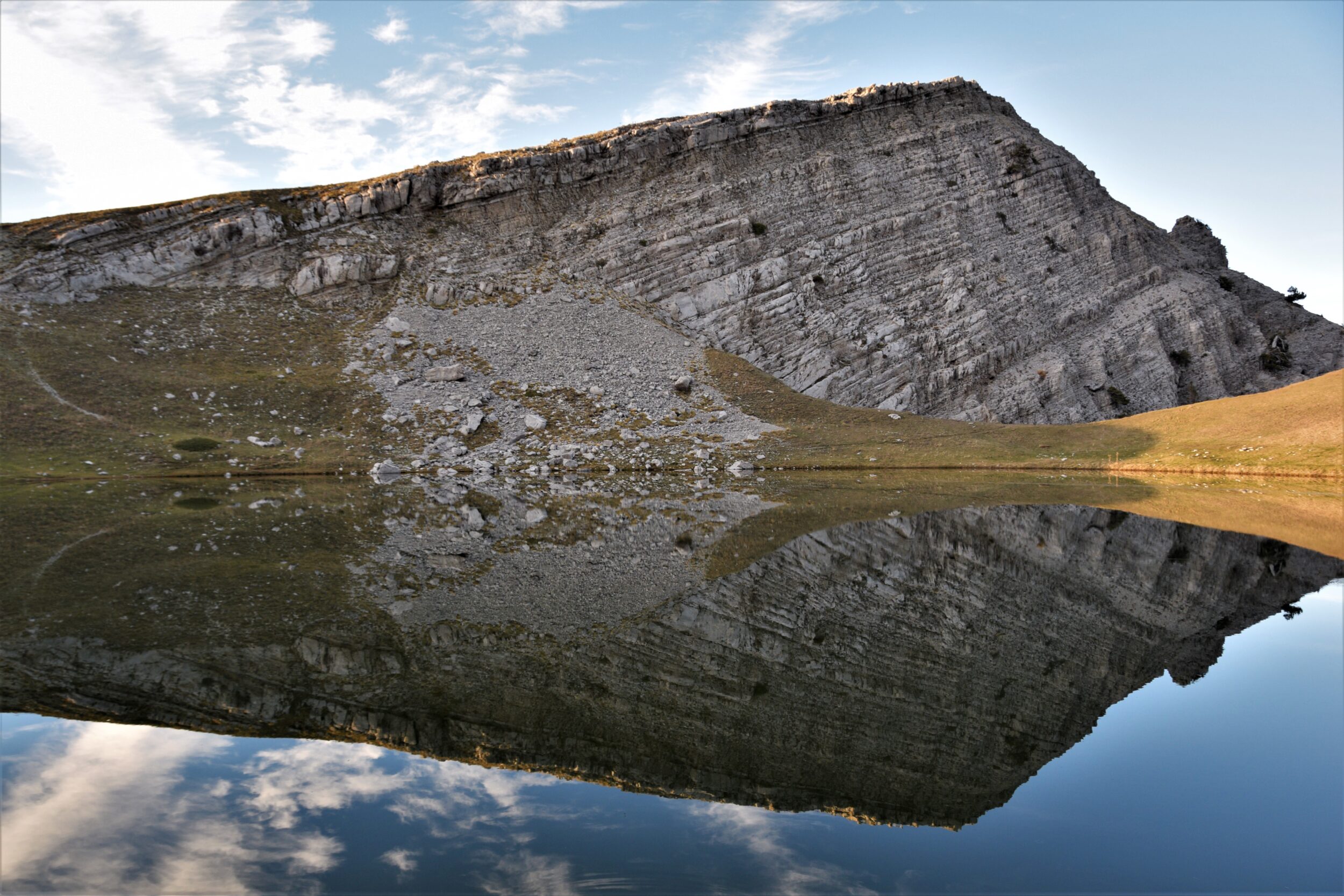 rugged cliffside reflecting in a still mountain lake