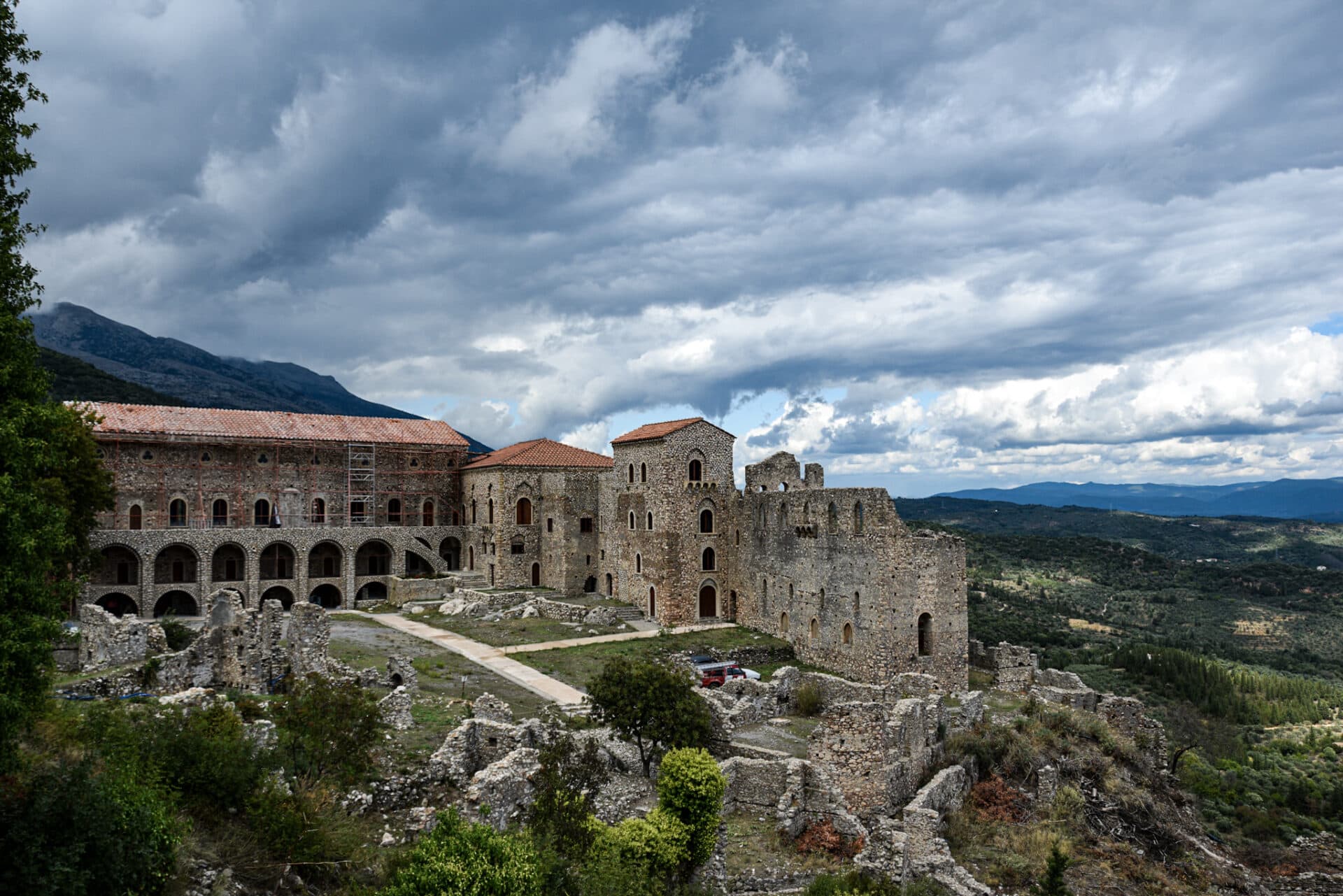 reconstructed Byzantine palace behind a couple of crumbling ruins on the verdant slopes of a hill