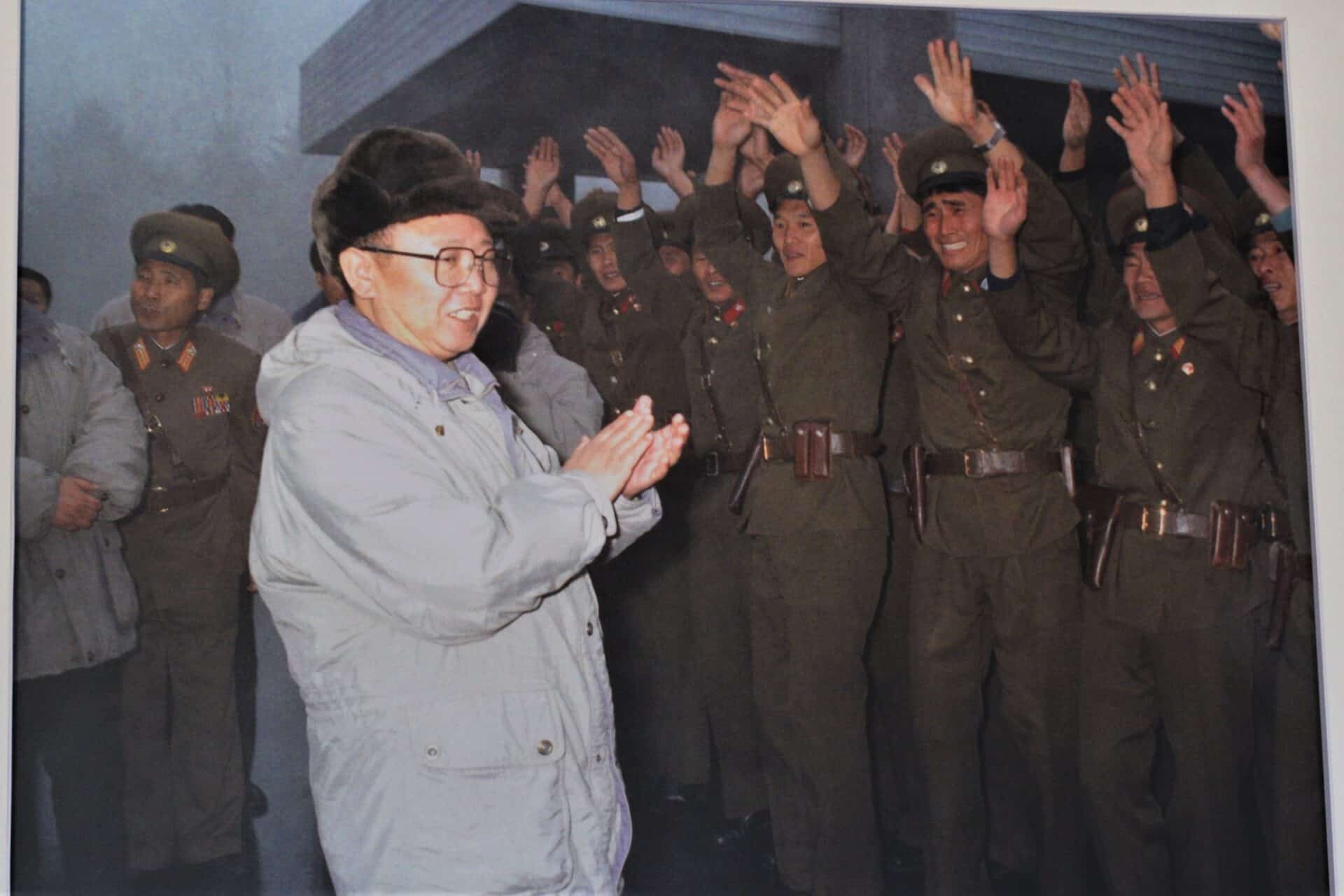 North Korean soldiers waving their hands above their heads worshiping Kim Jong-il clapping in front of them