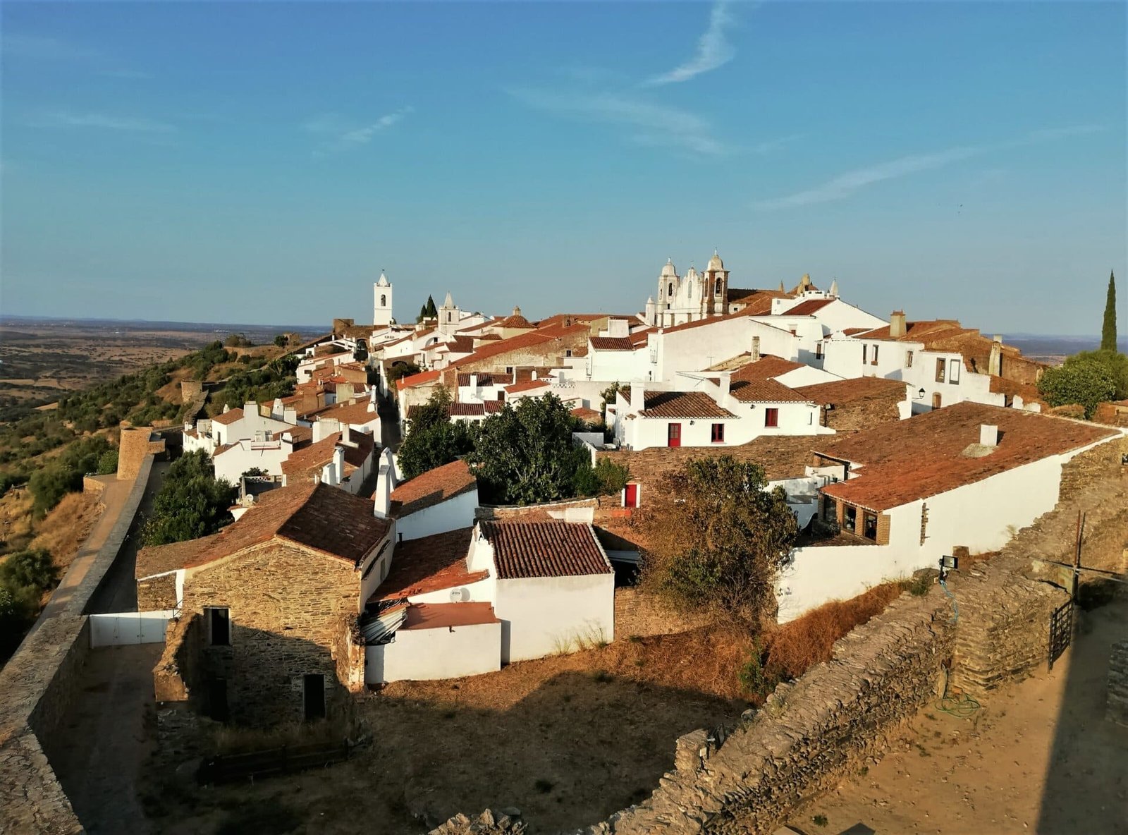 the setting sun falls on a whitewashed village on a fortified hill in Portugal's hinterland