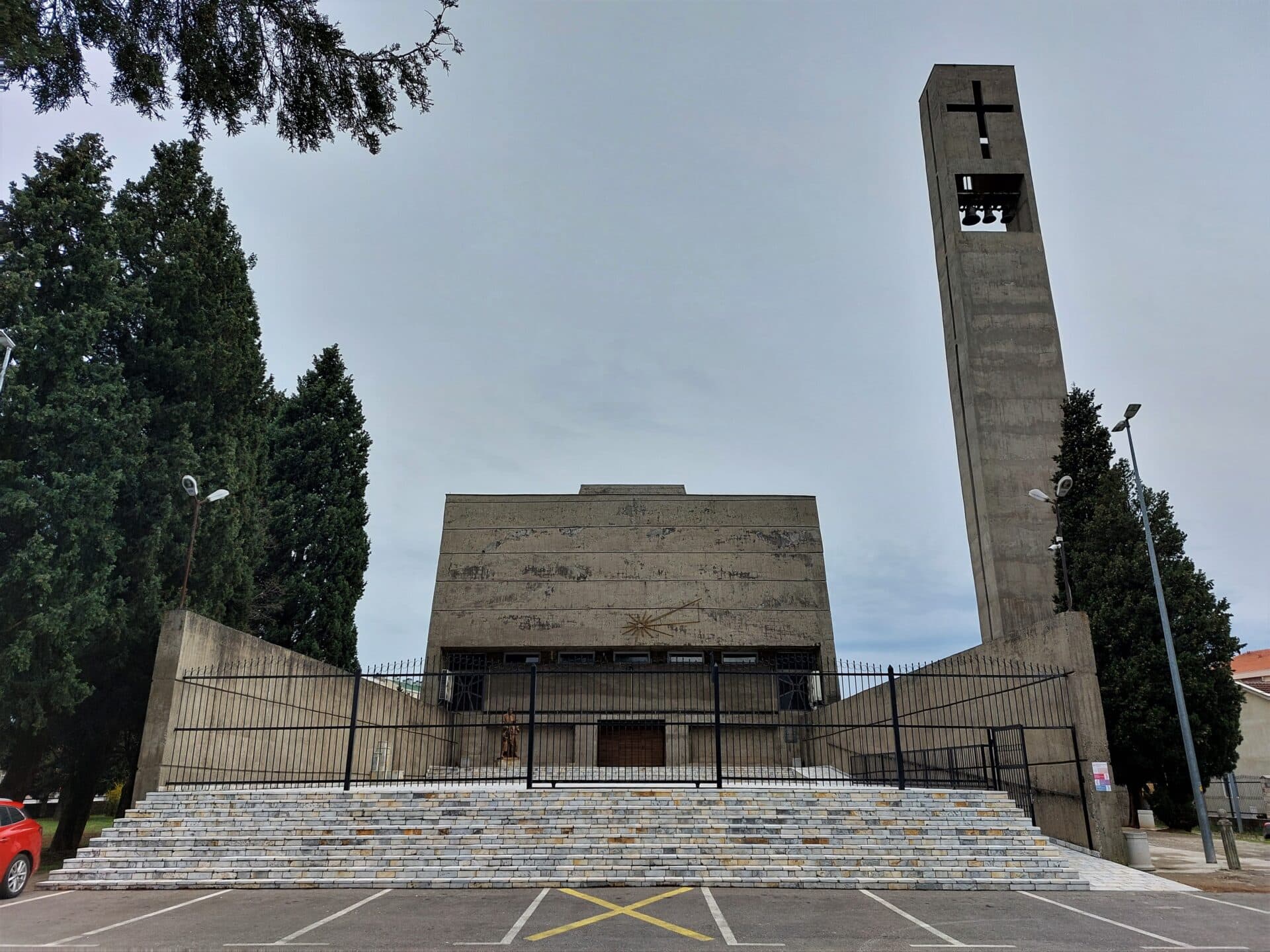 stairs blocked by a metal fence lead up to a rare catholic church in the brutalist style