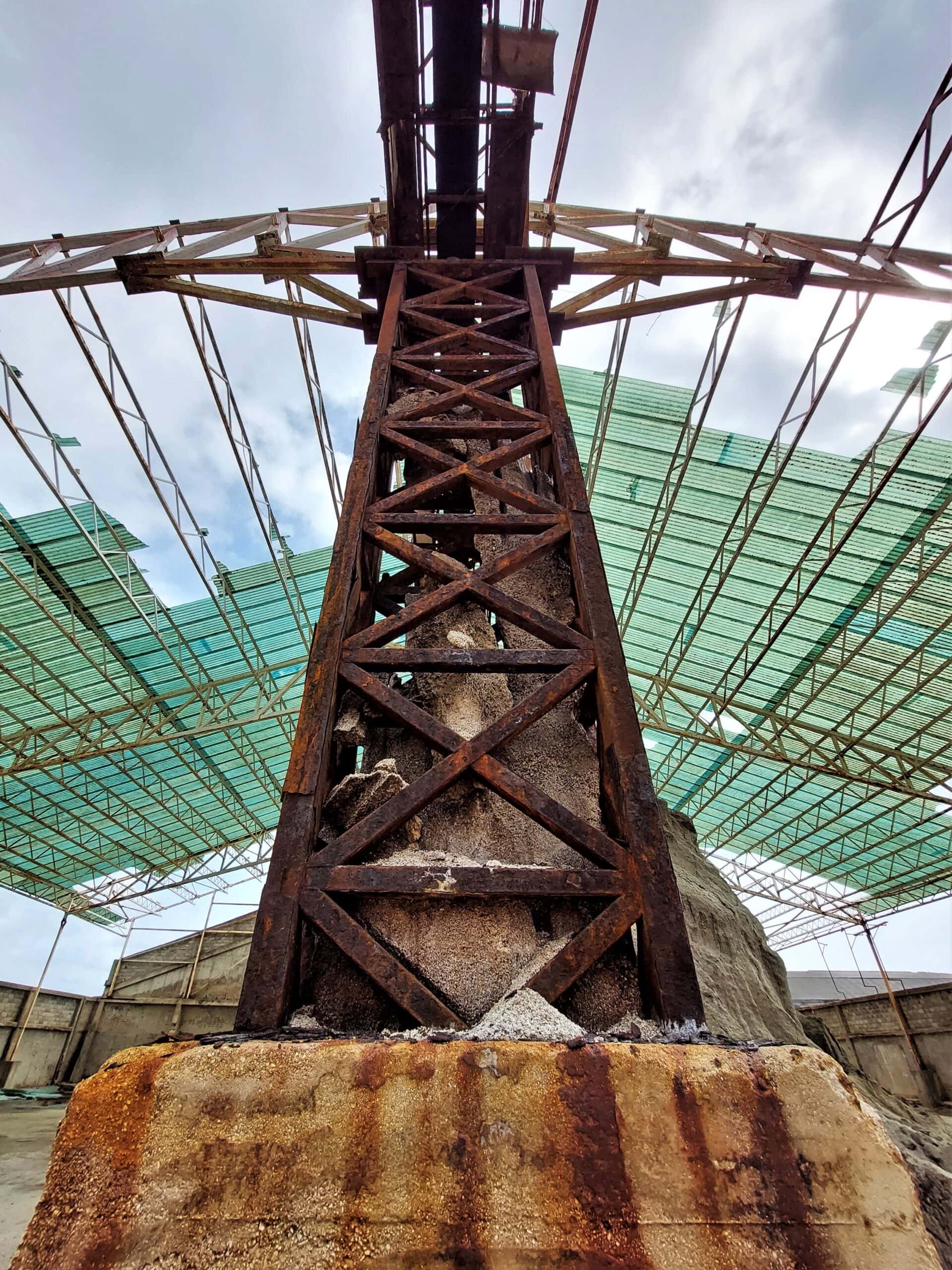 a rusting steel pillar holding up the remains of a warehouse roof