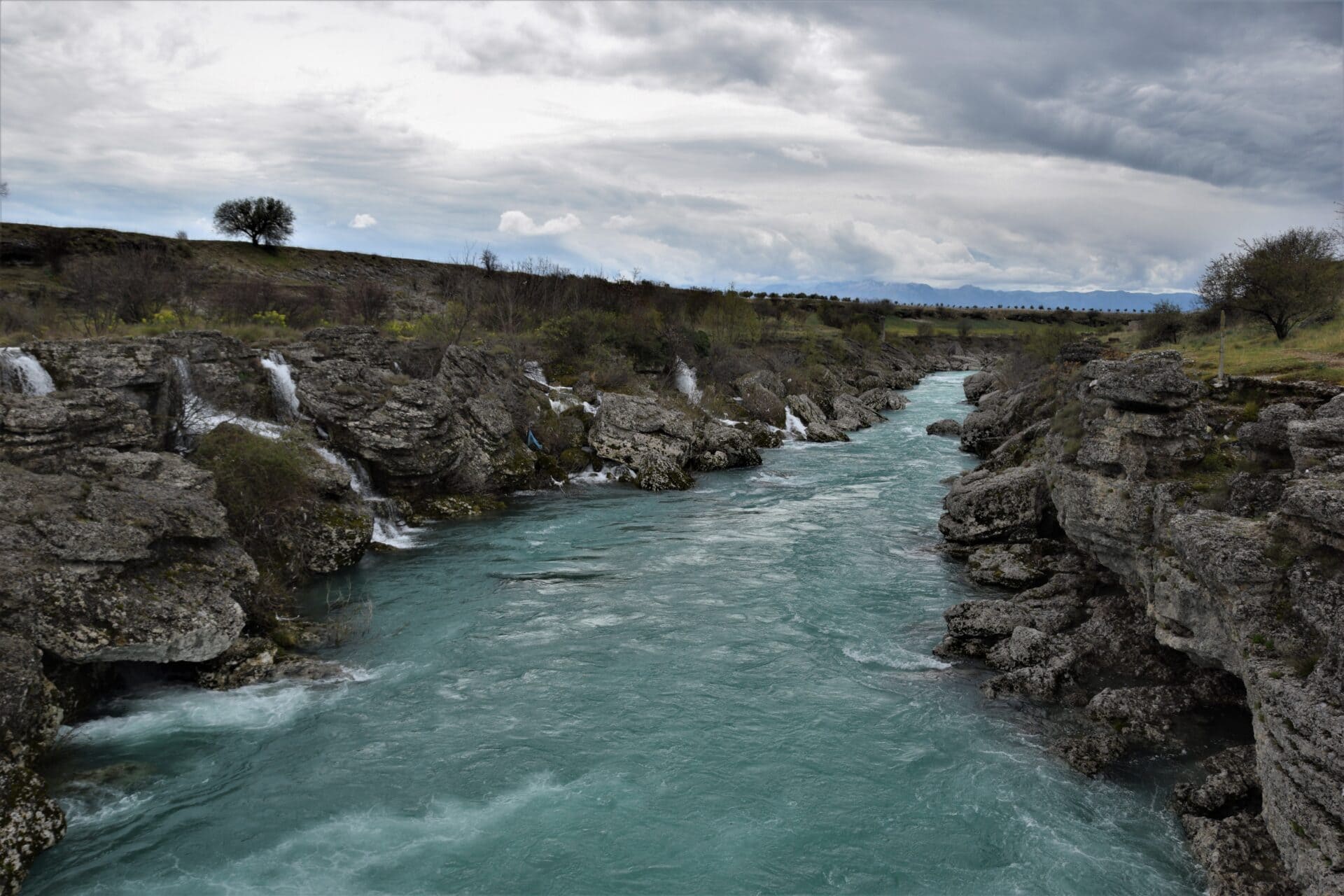 an emerald river flows through a canyon cut into the karst stone