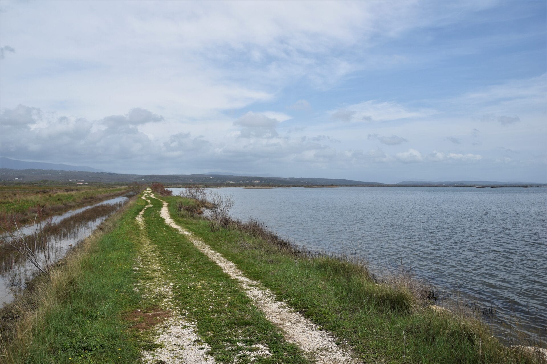 a dirt path runs along the shores of a lake