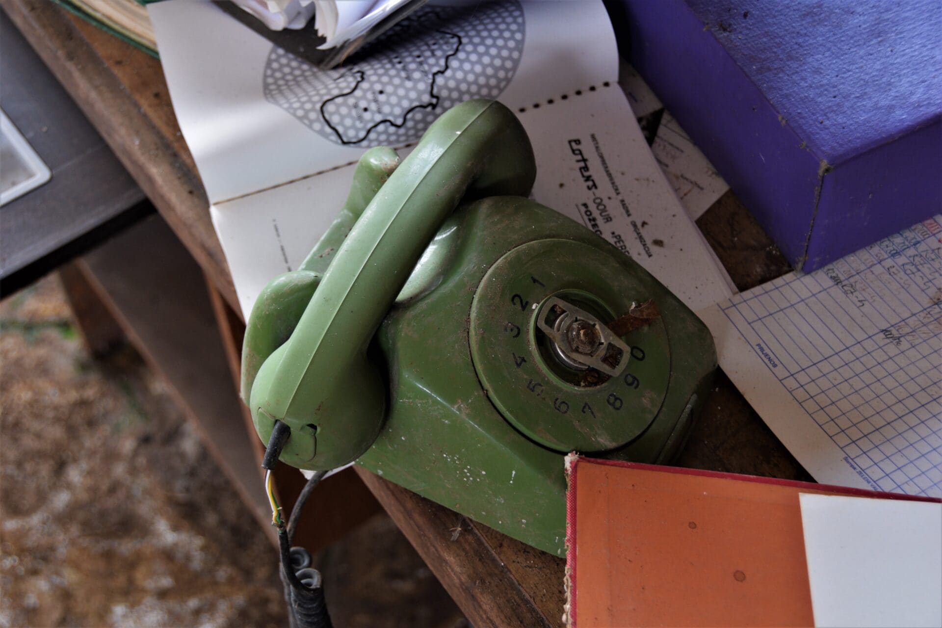 a green corded telephone on a wooden table