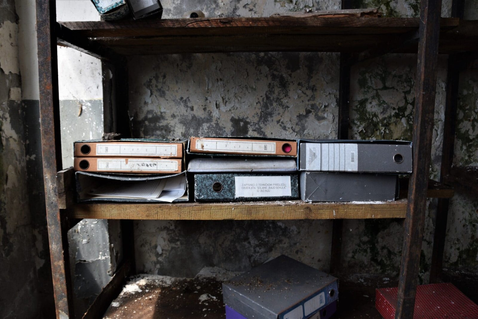 brown and grey folders lying in an old, rotting shelf