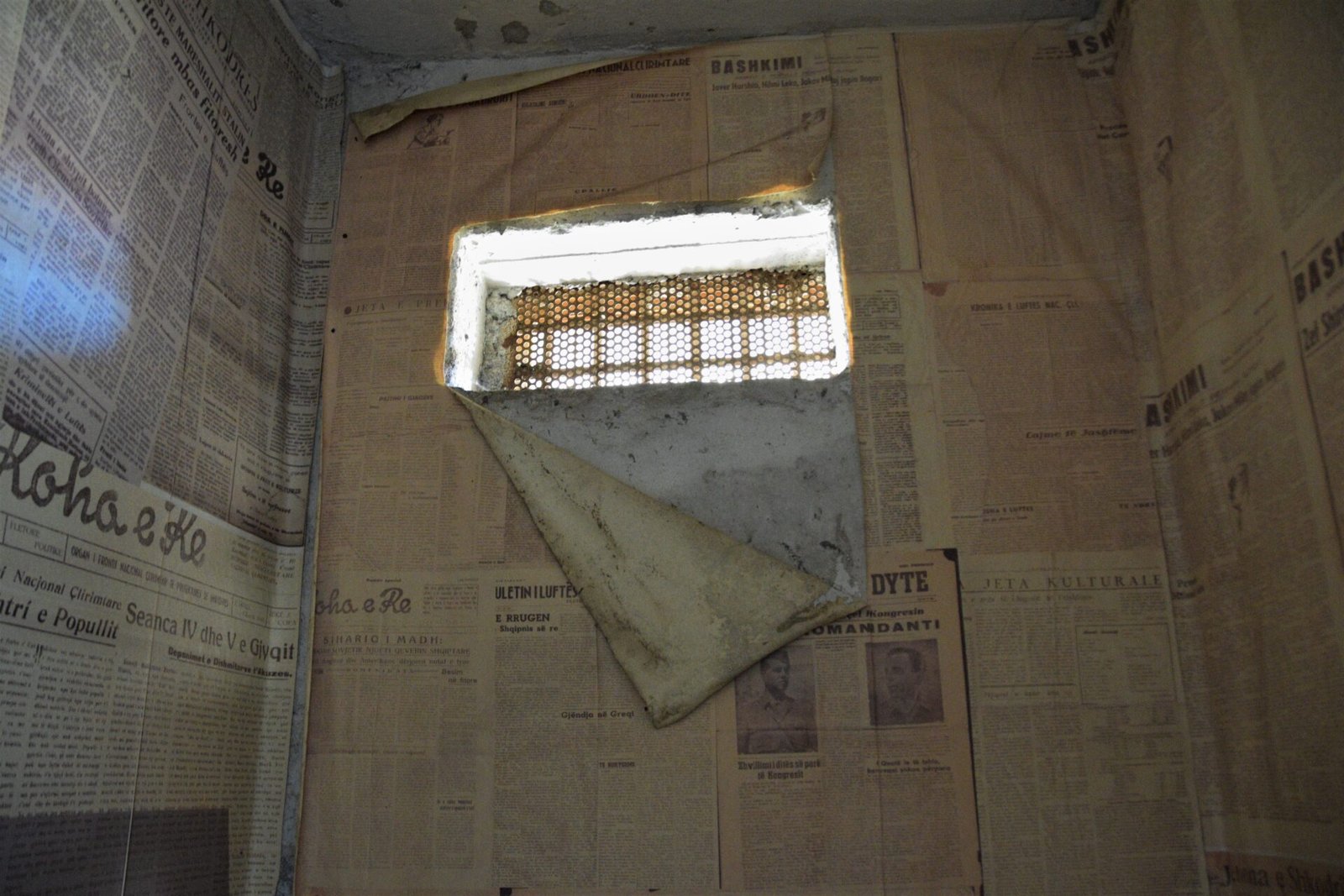old newspapers cover the walls of a prison cell