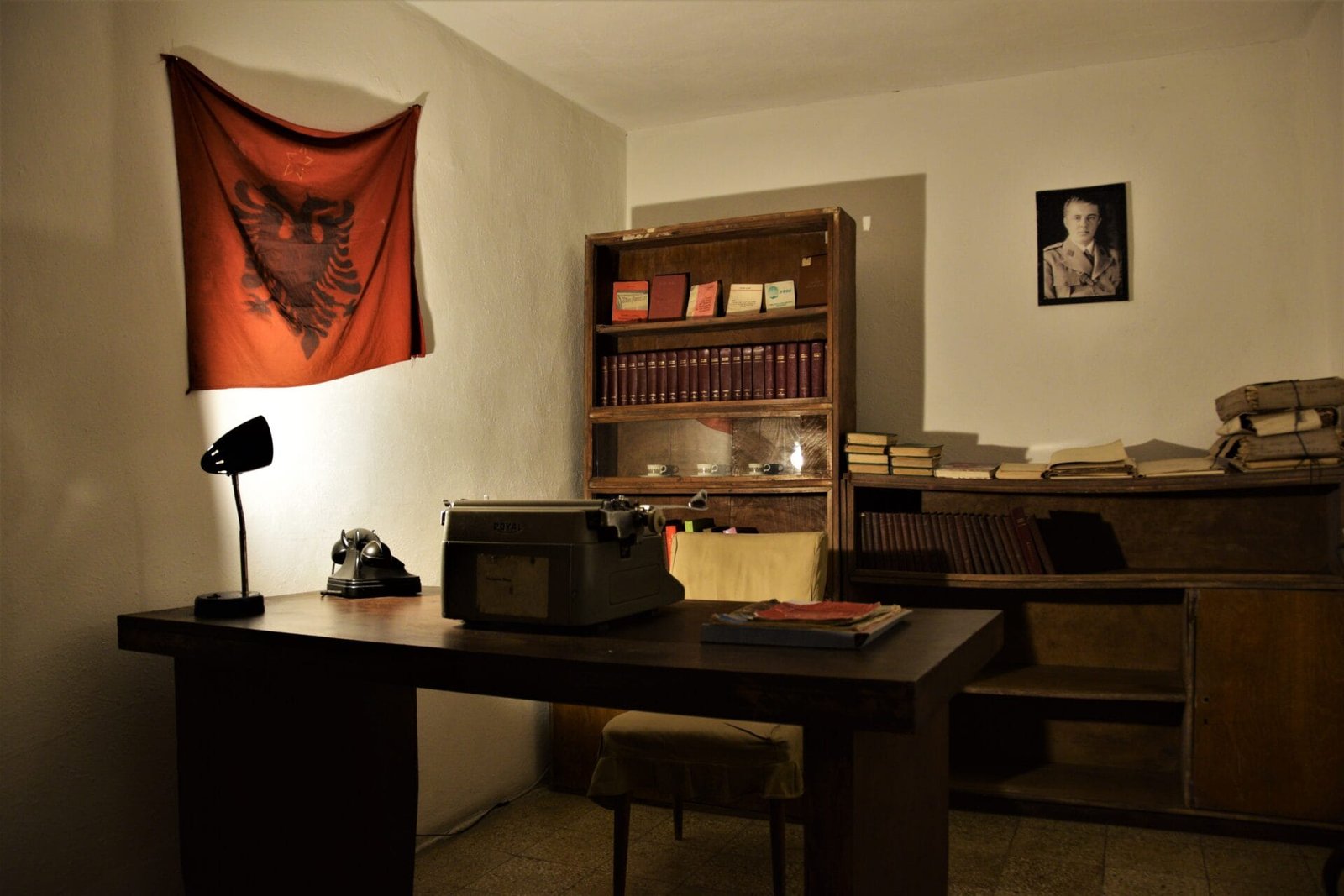an Albanian flag decorates the wall in a showroom displaying an office from communist times
