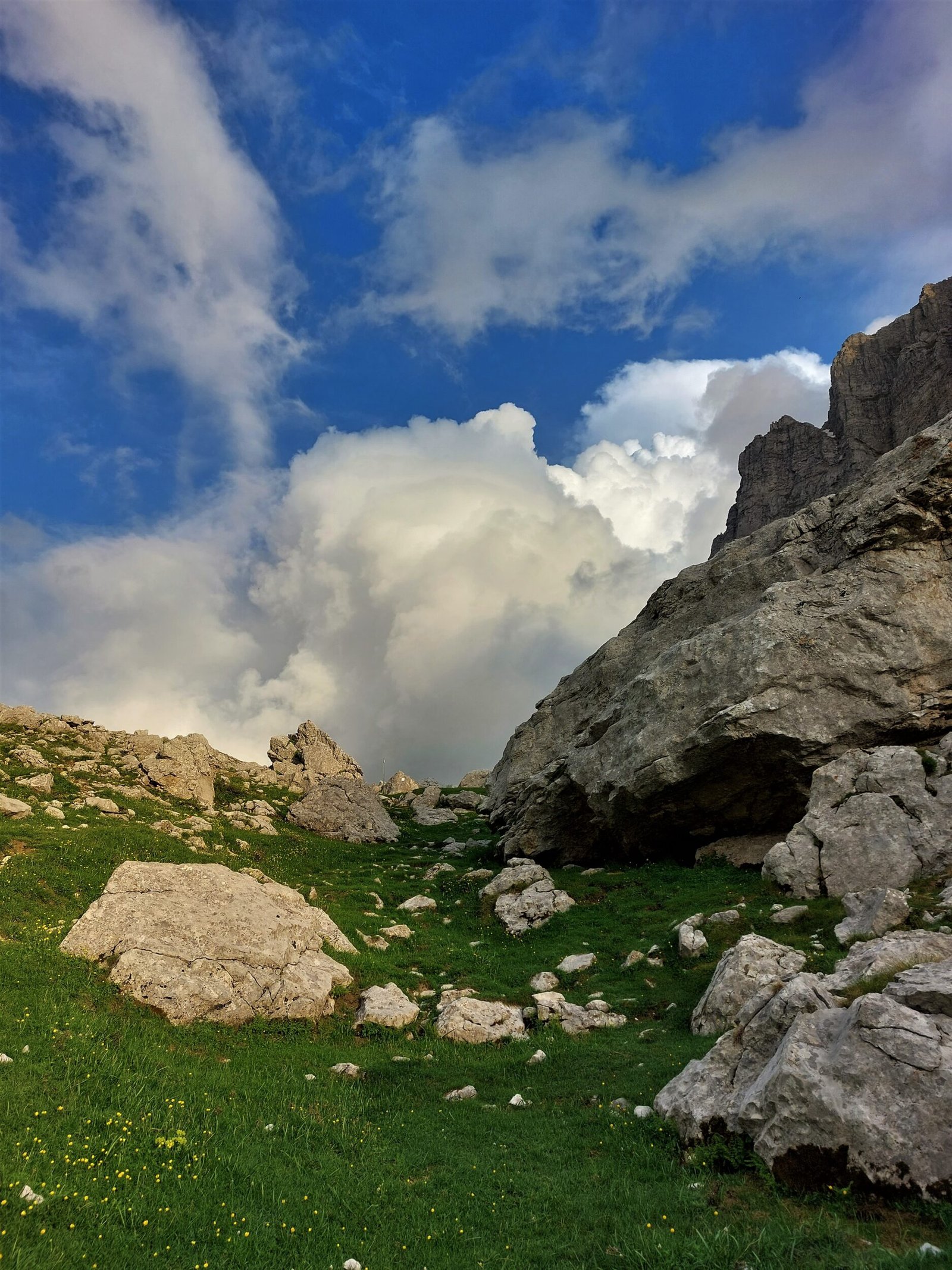 clouds tower above a rock-strewn slope