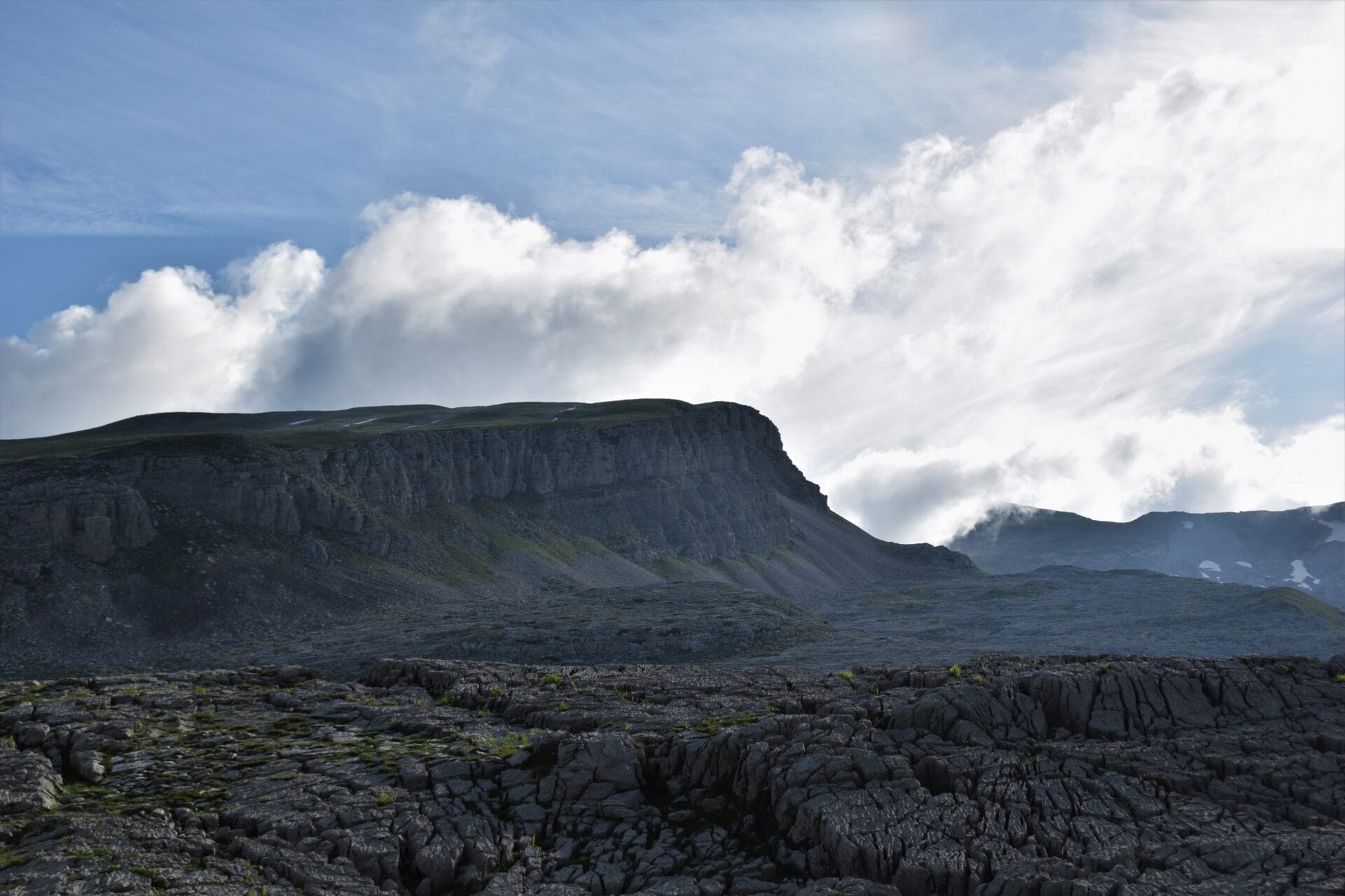a slanted peak looms above a rocky mountain landscape