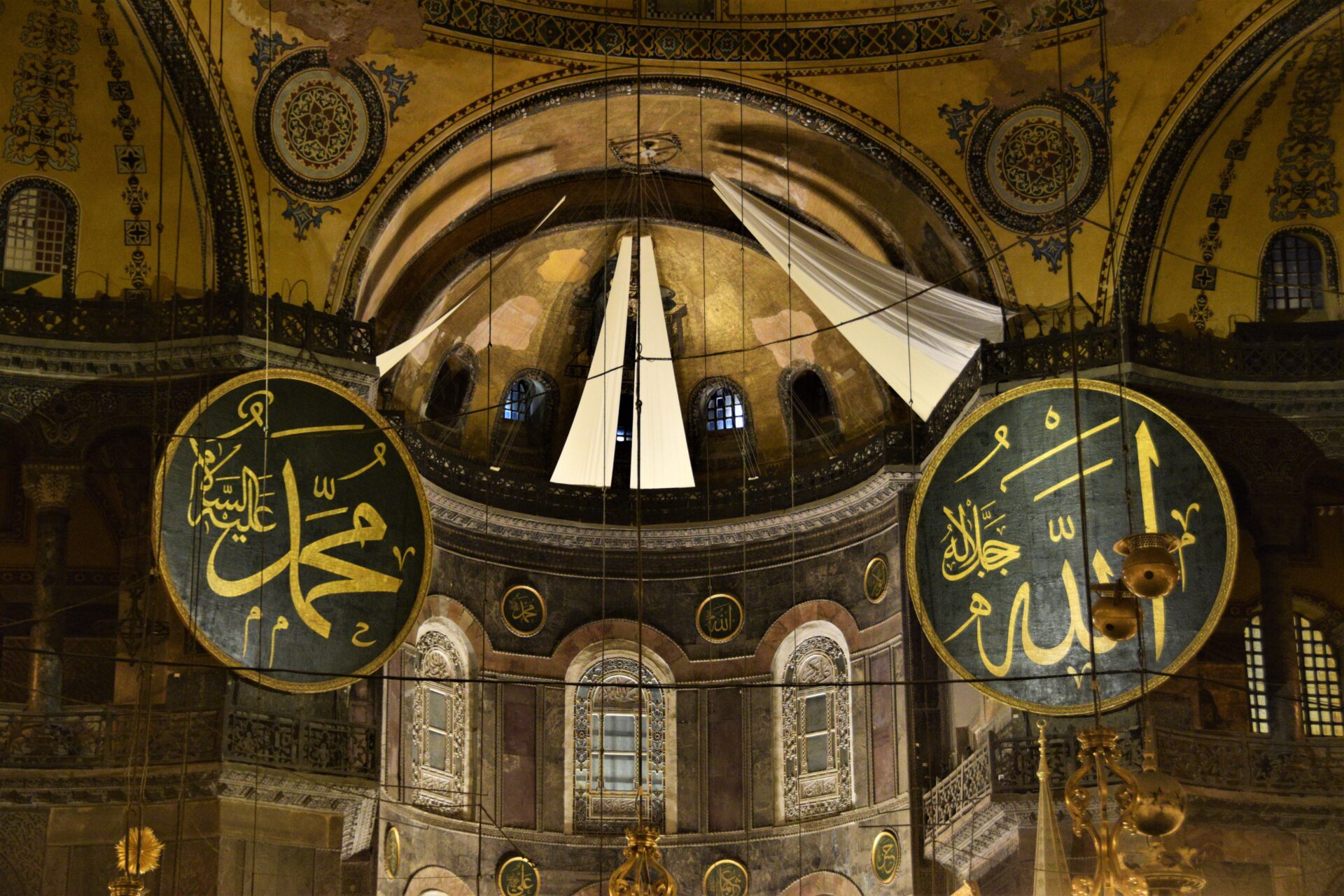 two big green discs with golde nframe and letters, depicting the names of the prophet Mohammed and Allah, hang inside the Hagia Sophia