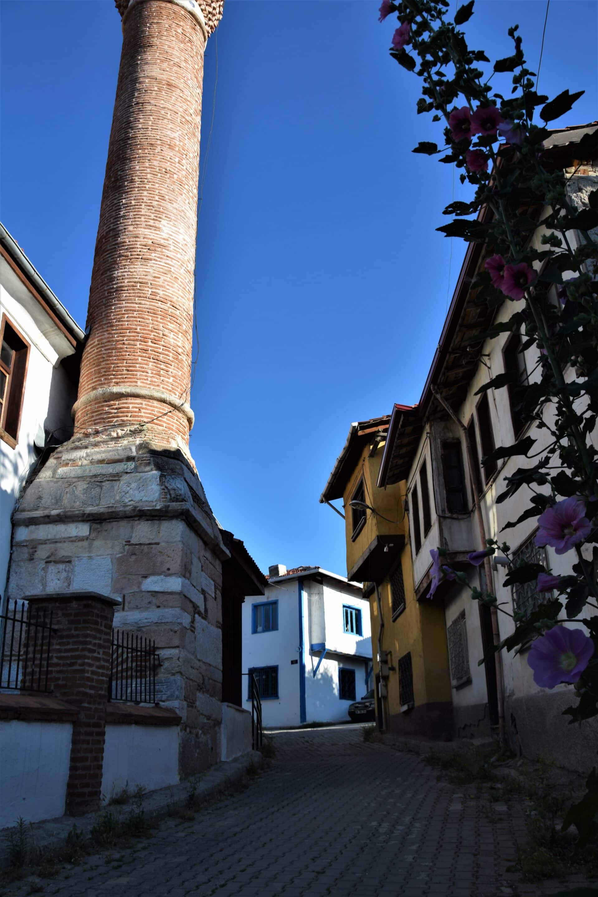 a cobblestone street leads past a brick minaret in an old Ottoman neighbourhood