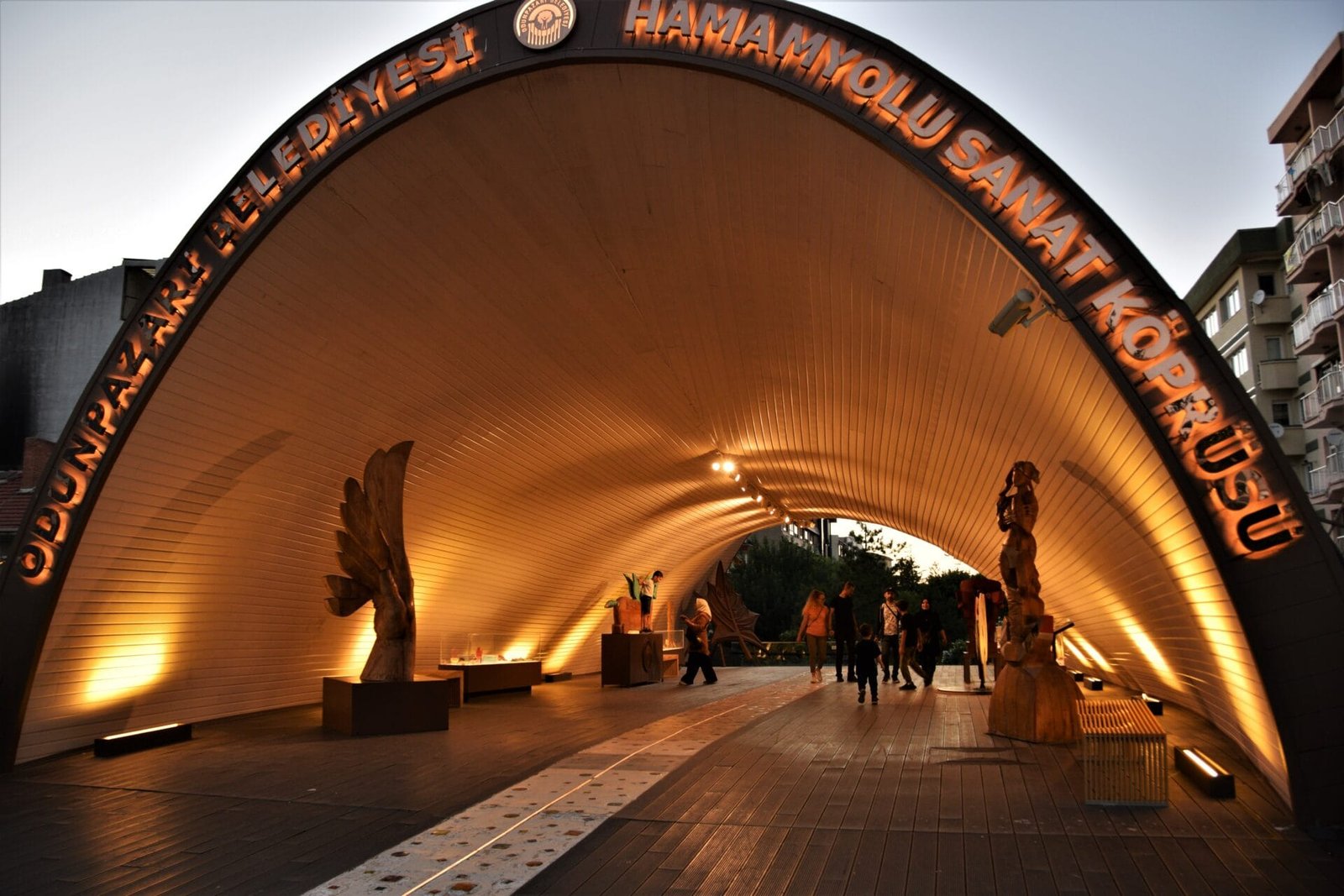 an arched, wooden roof covers art exhibits on a pedestrian bridge in Eskisehir