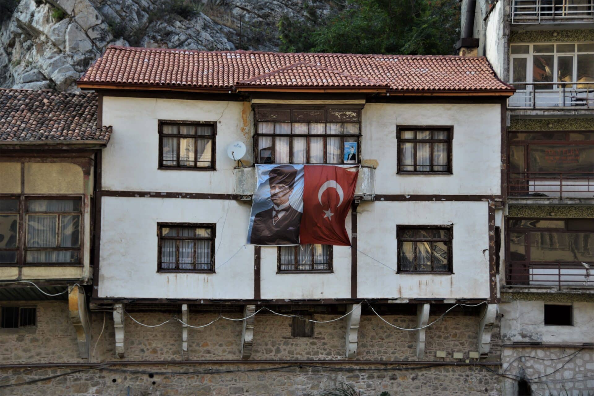 two banners, depicting Atatürk and the Turkish flag, hang from a balcony of an old Ottoman house