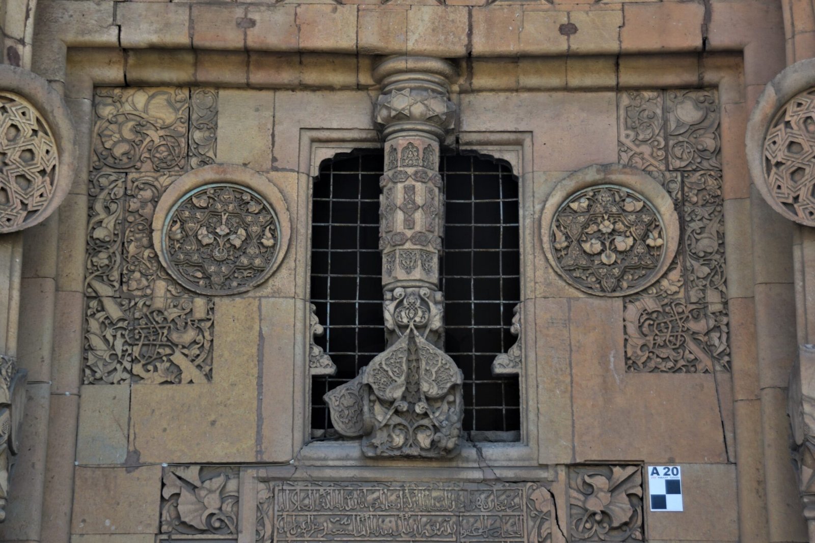 richly ornamented stone column in front of a small window adorning the main gate of a Seljuk hospital in Divrigi
