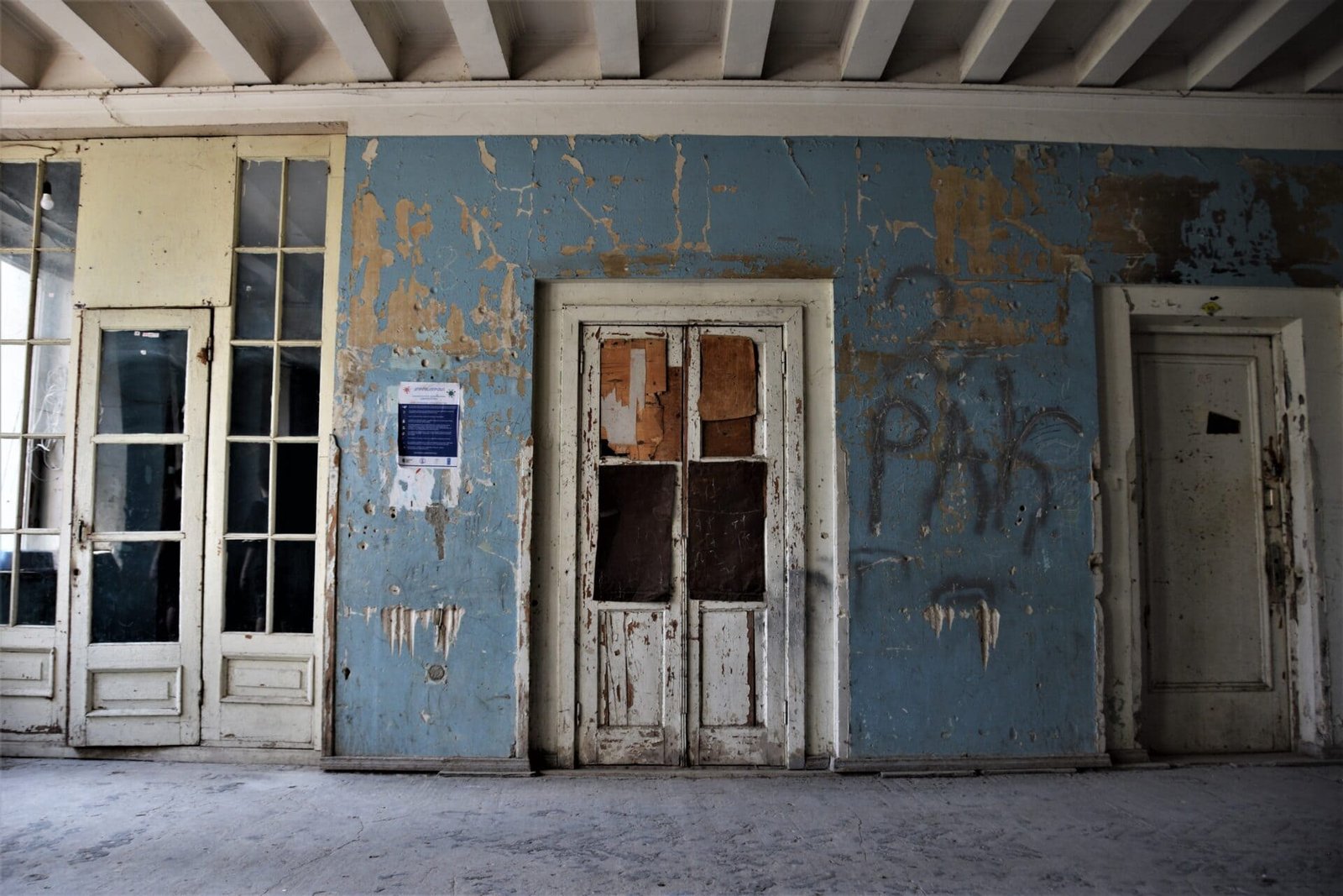 weathered doors in a blue corridor of an abandoned building
