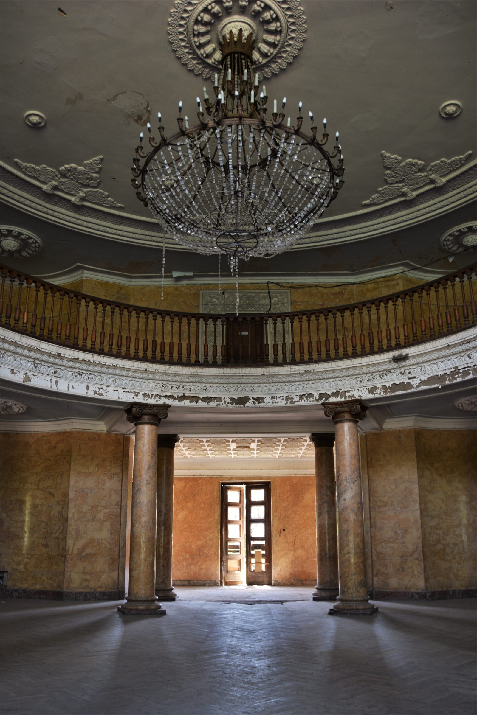 a lustre hangs in a marbel entrance hall of an old Soviet sanatorium
