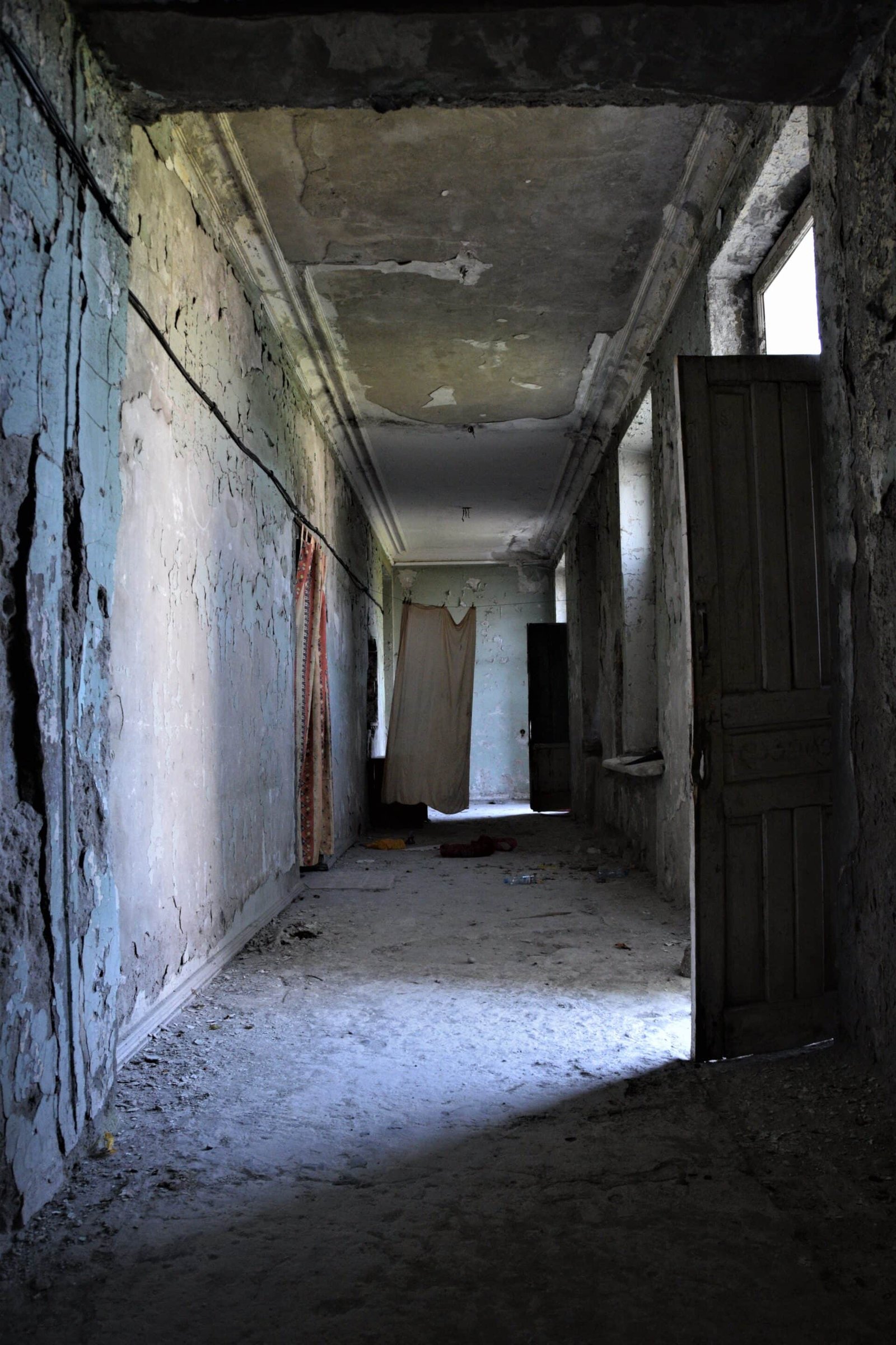light falls through an open door into a derelict hallway of a former sanatorium