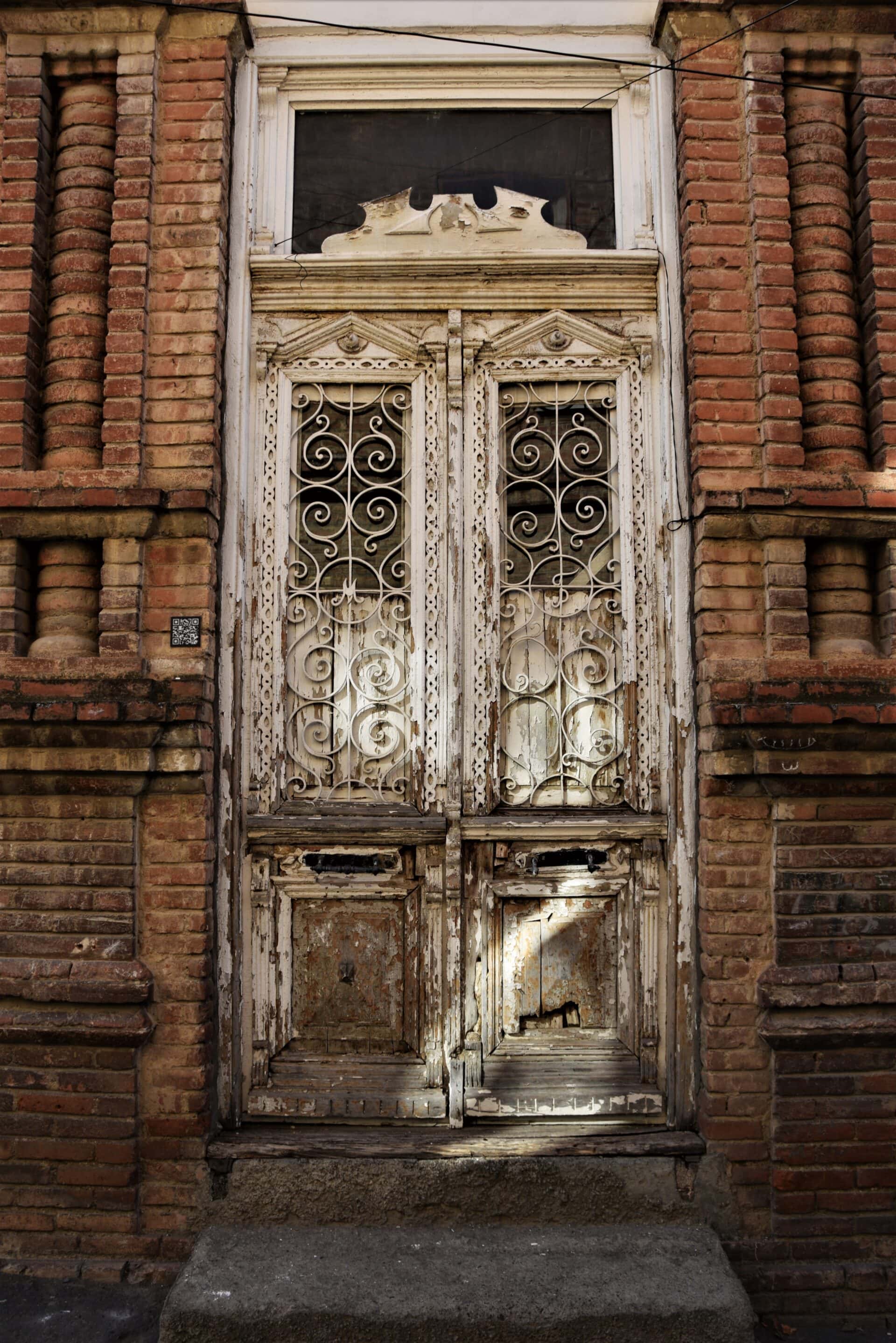 sun rays fall on a weathered white wooden door of a red brick house
