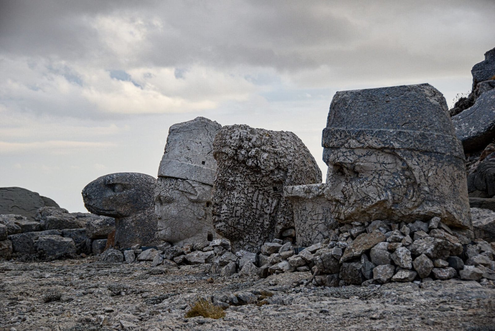 four decapitated heads of god statues sit on the rocky ground on Mount Nemrut