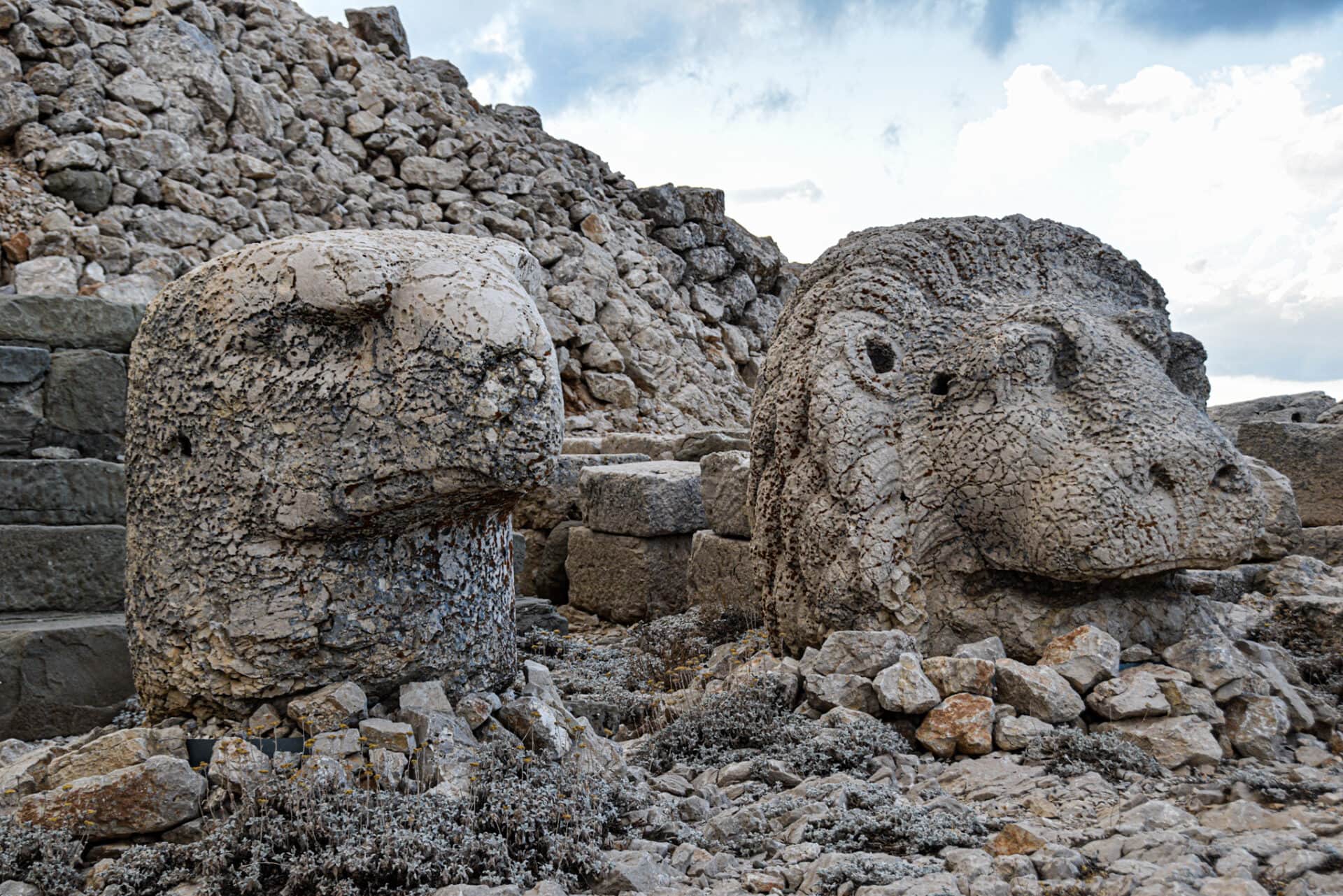 the decapitated stone heads of a lion and eagle statue sit on the rocky ground on Mount Nemrut