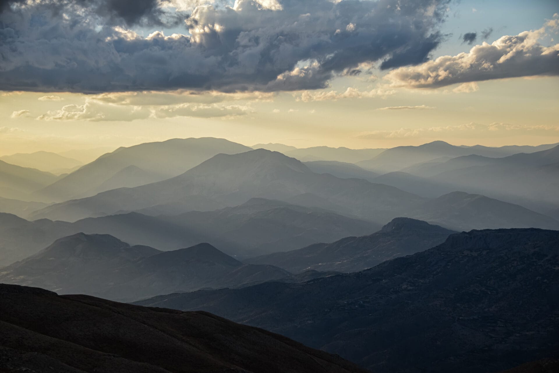 fleeting rays of sun fall onto a layered mountain panorama