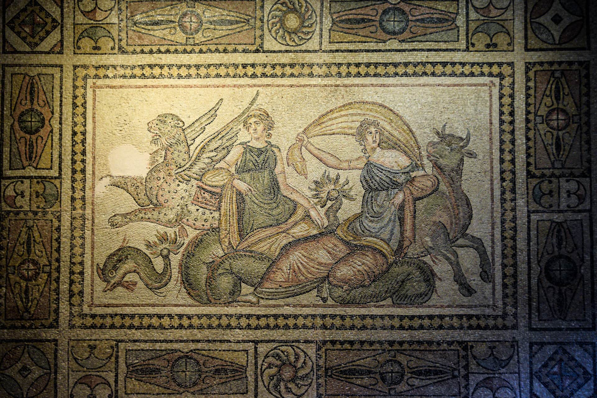 a magnificent ROman mosaic depicting two women, a bull, and a winged jaguar
