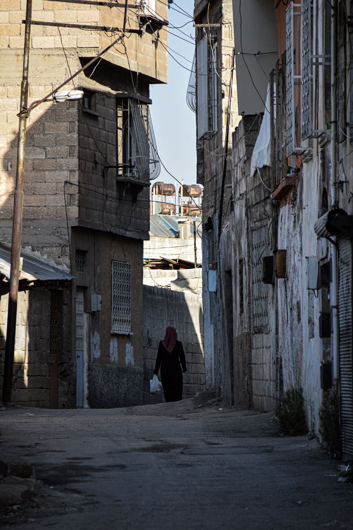 a Muslim woman walking down a concrete sidestreet in Gazianteps old town