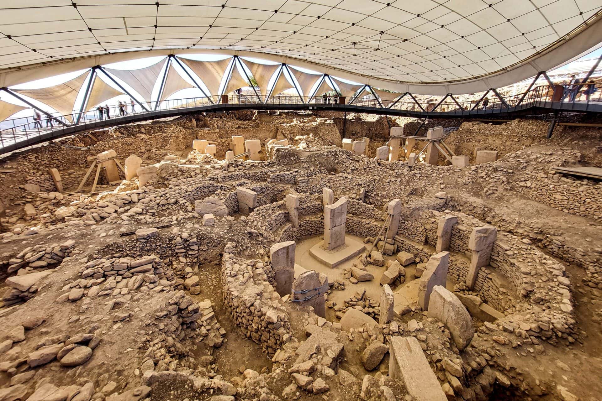 an excavation site showing several circular monolithic buildings featuring massive t-shaped pillars in Göbekli Tepe