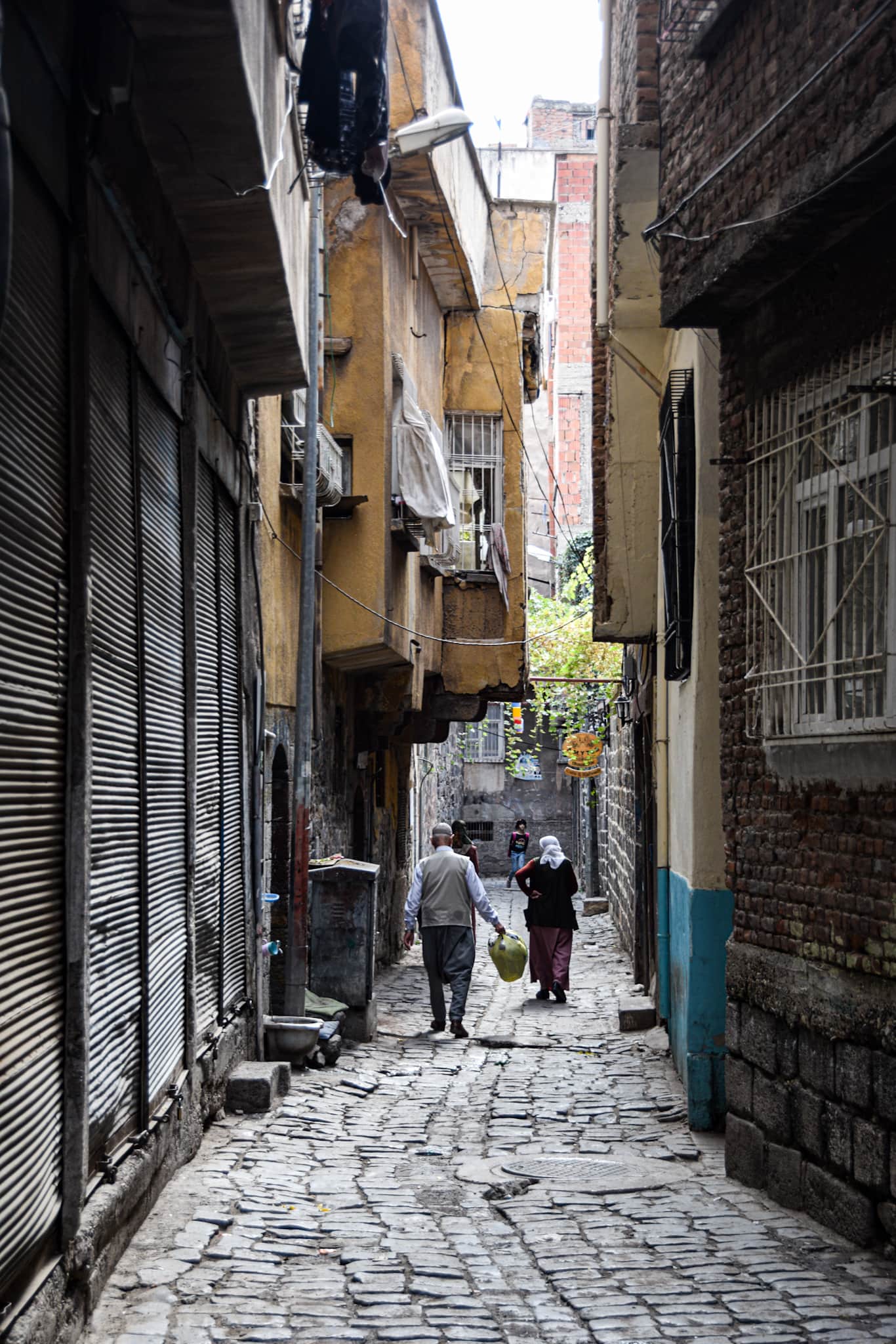 a man and a women wlak down a narrow cobbled sidealley in Diyarbakir's old town
