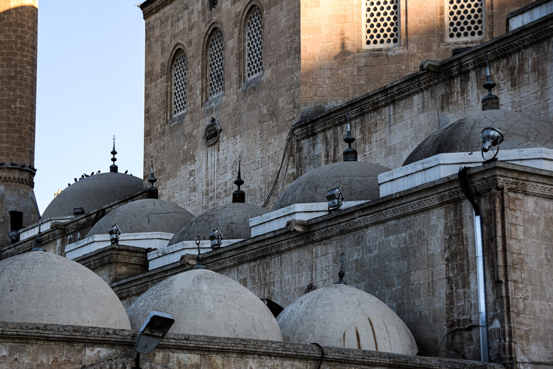 several domes on the lower roof of a mosque