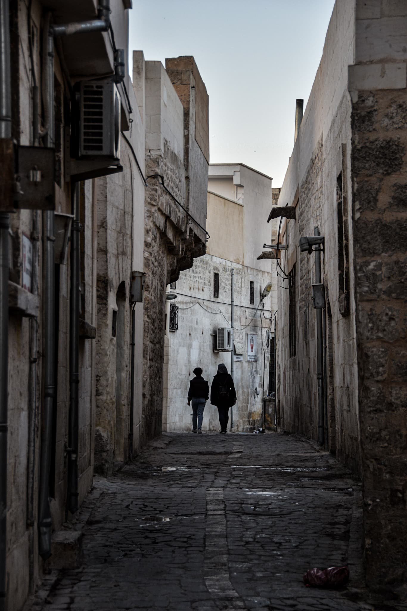 two women walk down a dim cobbled alley in Sanliurfa's old town