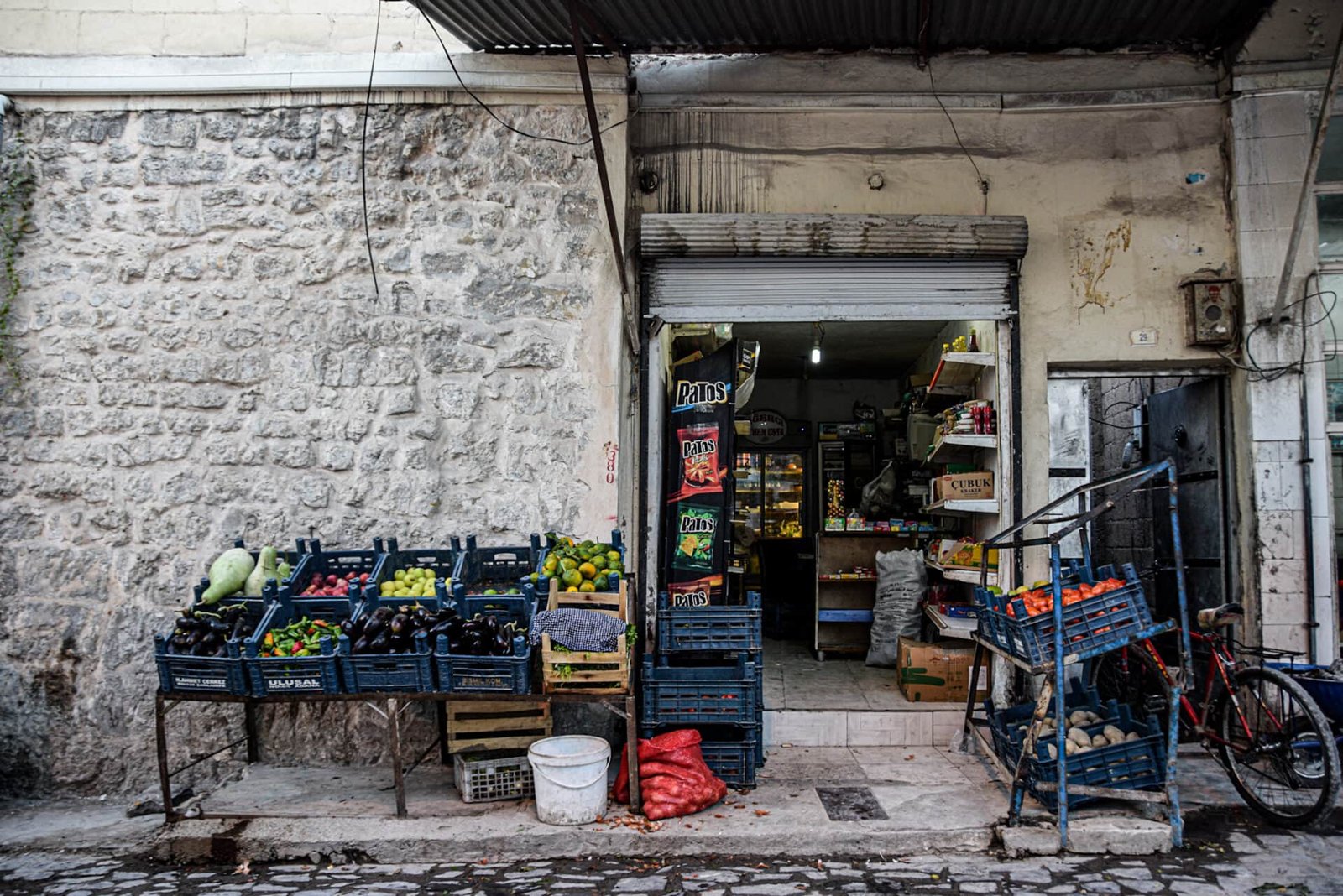 blue shelves filled with fruits and vegetables in front of a small shop in Sanliurfa's old town