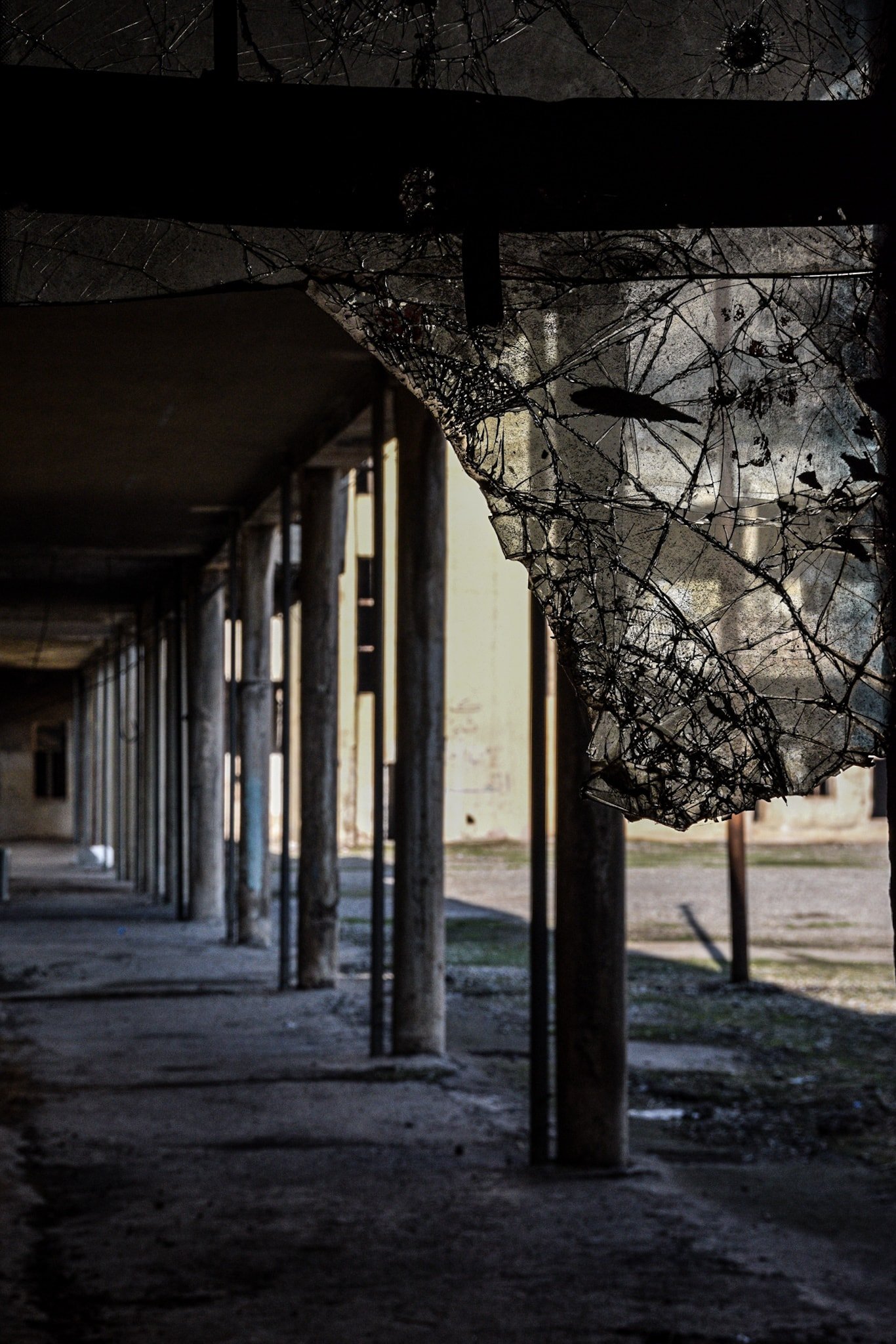 a portico in an abandoned prison seen through a broken window