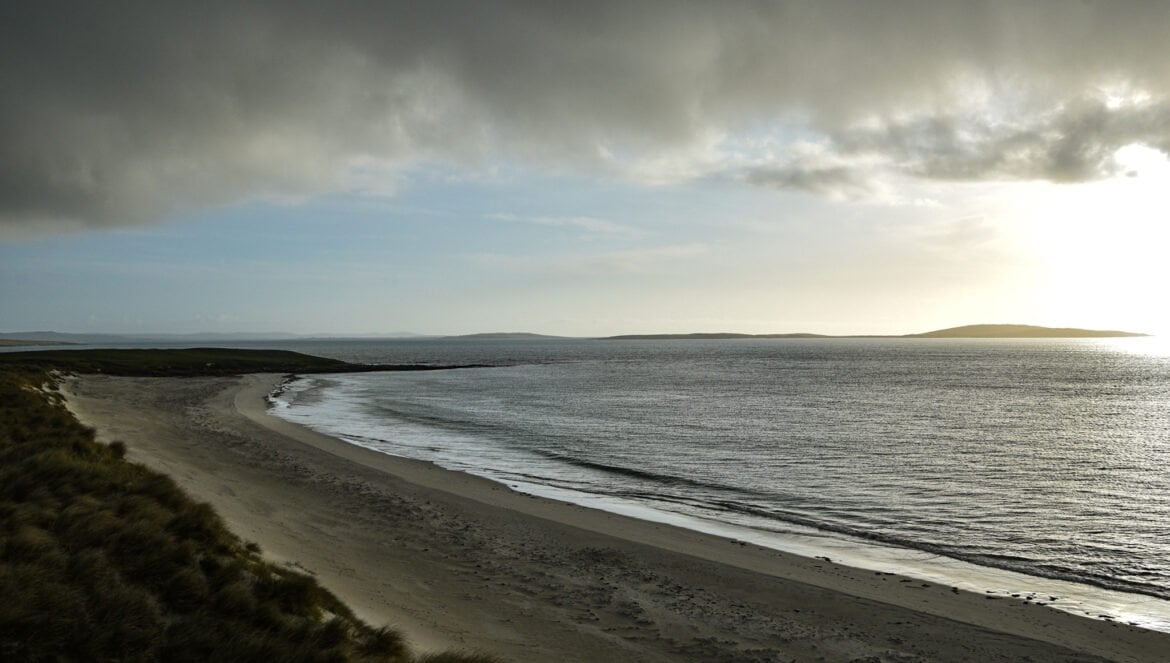 the sun sets oevr a secluded, sandy beach on the island of Berneray