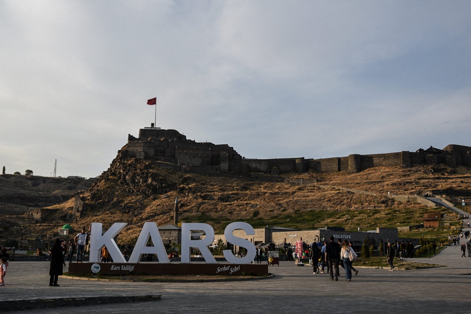 a "Kars" city sign at the bottom of an imposing citadel