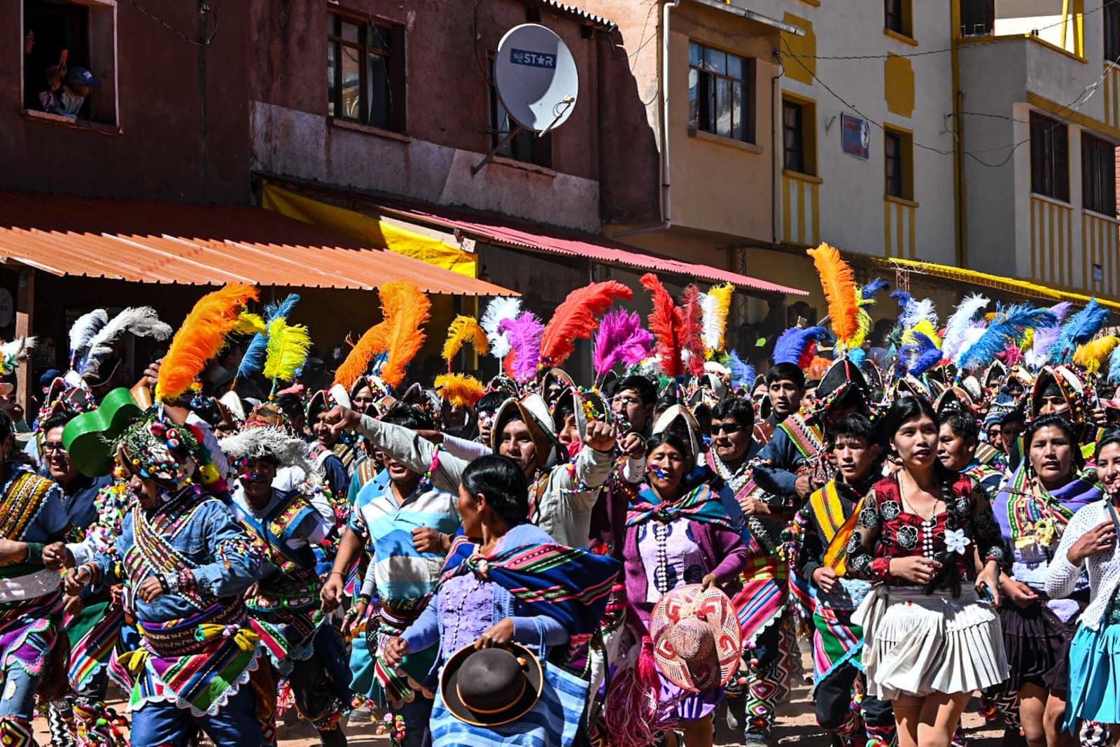 men and women clad in festive and colourful costumes dance around the main square in Macha during the celebrations of Tinku