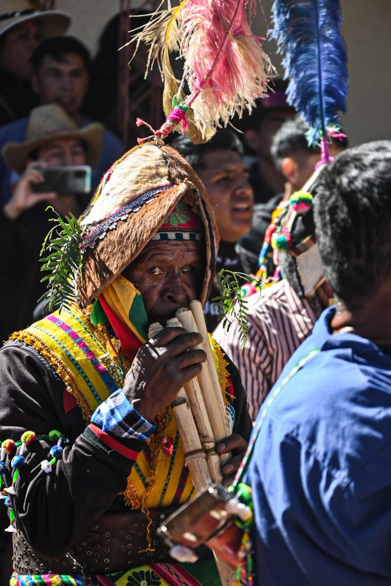 a man wearing a traditional helmet and traditional costume plays a pipe instrument during the Tinku festival in Macha